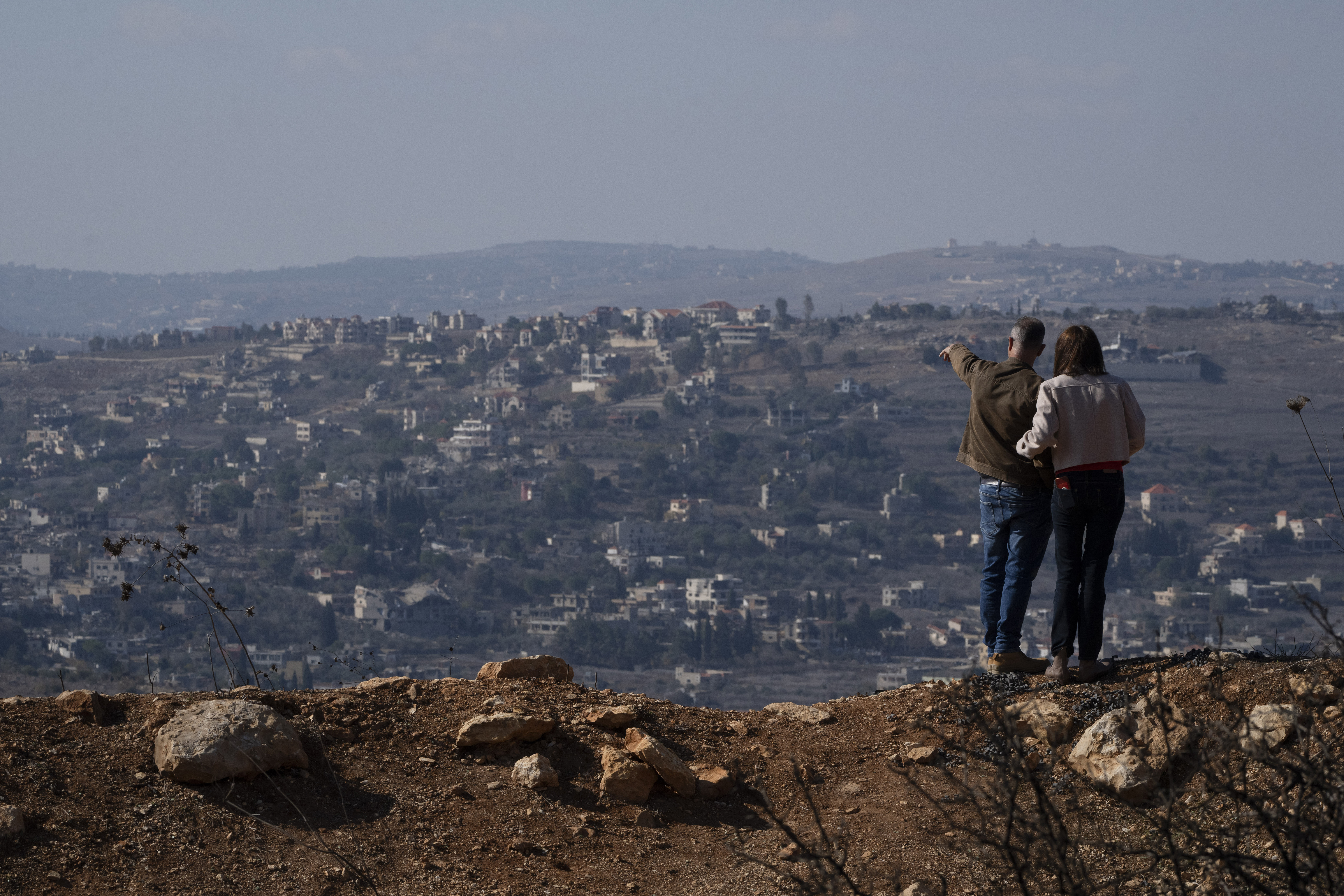 FILE - An Israeli couple can see buildings in southern Lebanon that were damaged during the war from an overlook in northern Israel, on Nov. 30, 2024. (AP Photo/Leo Correa, File)