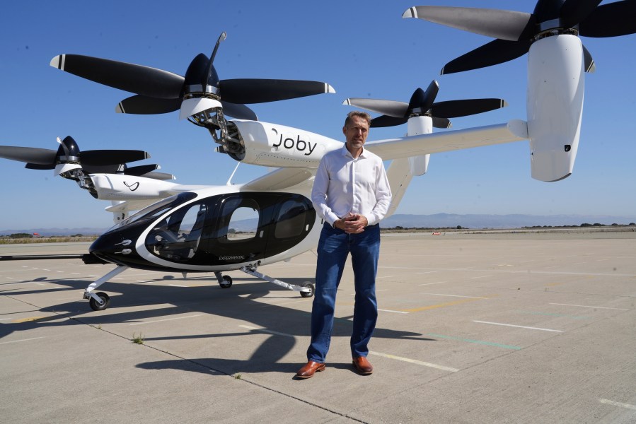 JoeBen Bevirt, CEO of Joby Aviation, stands next to an "electric vertical take-off and landing" aircraft, also known as an eVTOL, in Marina, Calif. on Monday, Oct. 7, 2024. (AP Photo/Terry Chea)