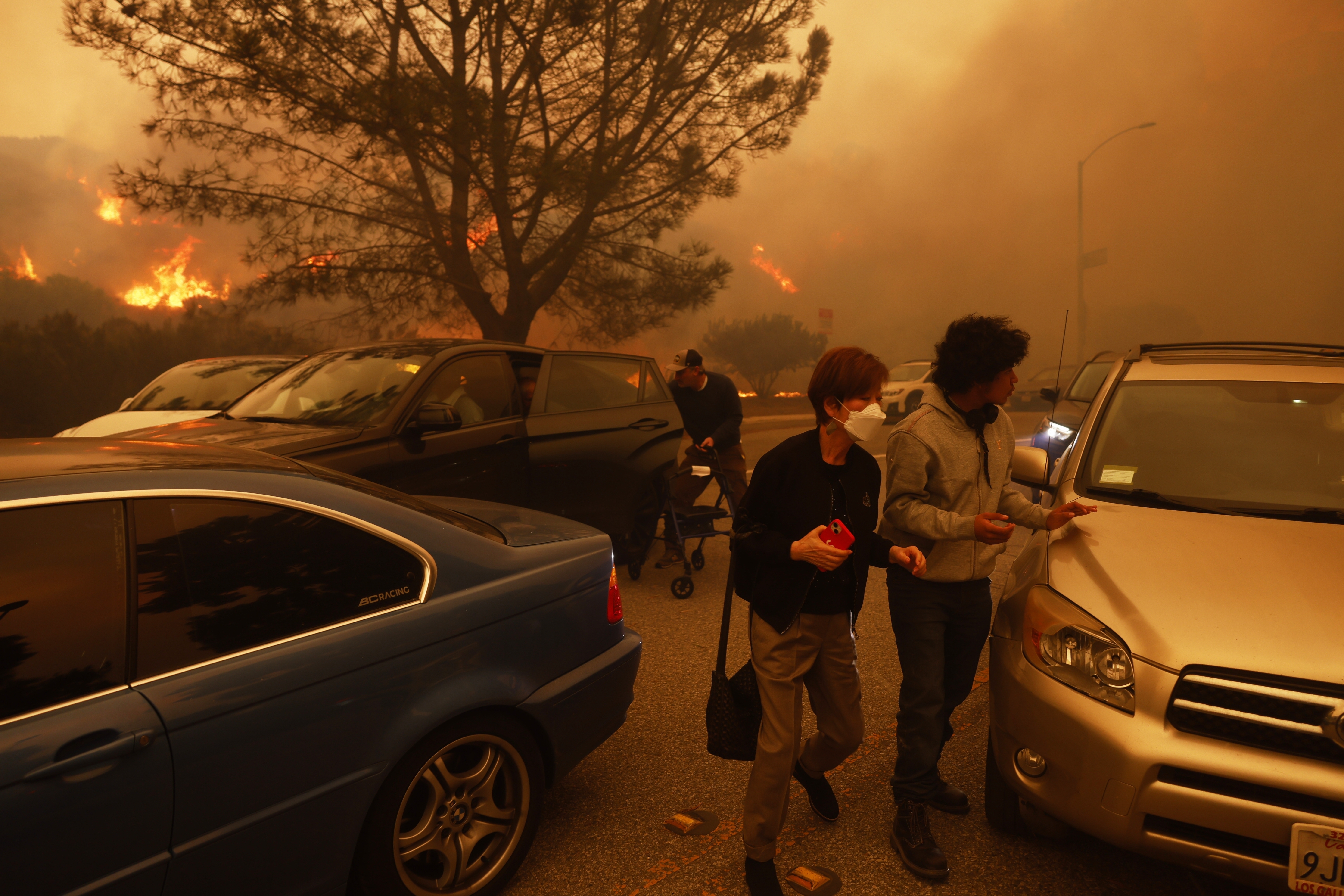 People flee from the advancing Palisades Fire, by car and on foot, in the Pacific Palisades neighborhood of Los Angeles Tuesday, Jan. 7, 2025. (AP Photo/Etienne Laurent)