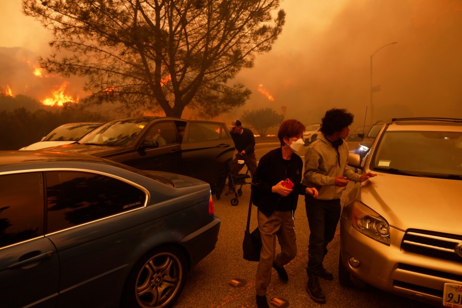 People flee from the advancing Palisades Fire, by car and on foot, in the Pacific Palisades neighborhood of Los Angeles Tuesday, Jan. 7, 2025. (AP Photo/Etienne Laurent)