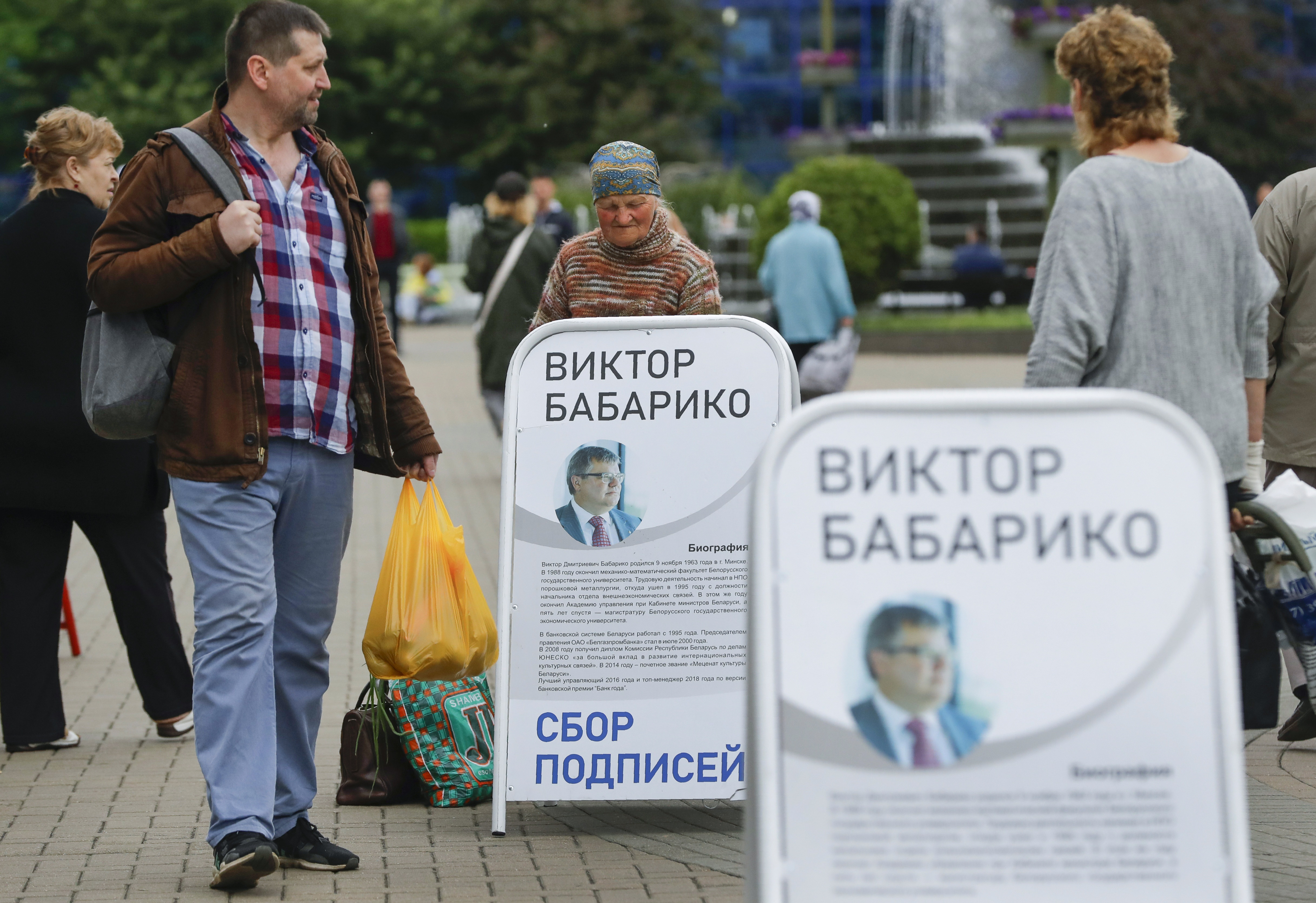 FILE - People walk past informational posters supporting Viktar Babaryka, who wanted to run in the upcoming presidential elections, in Minsk, Belarus, on June 14, 2020. (AP Photo/Sergei Grits, File)