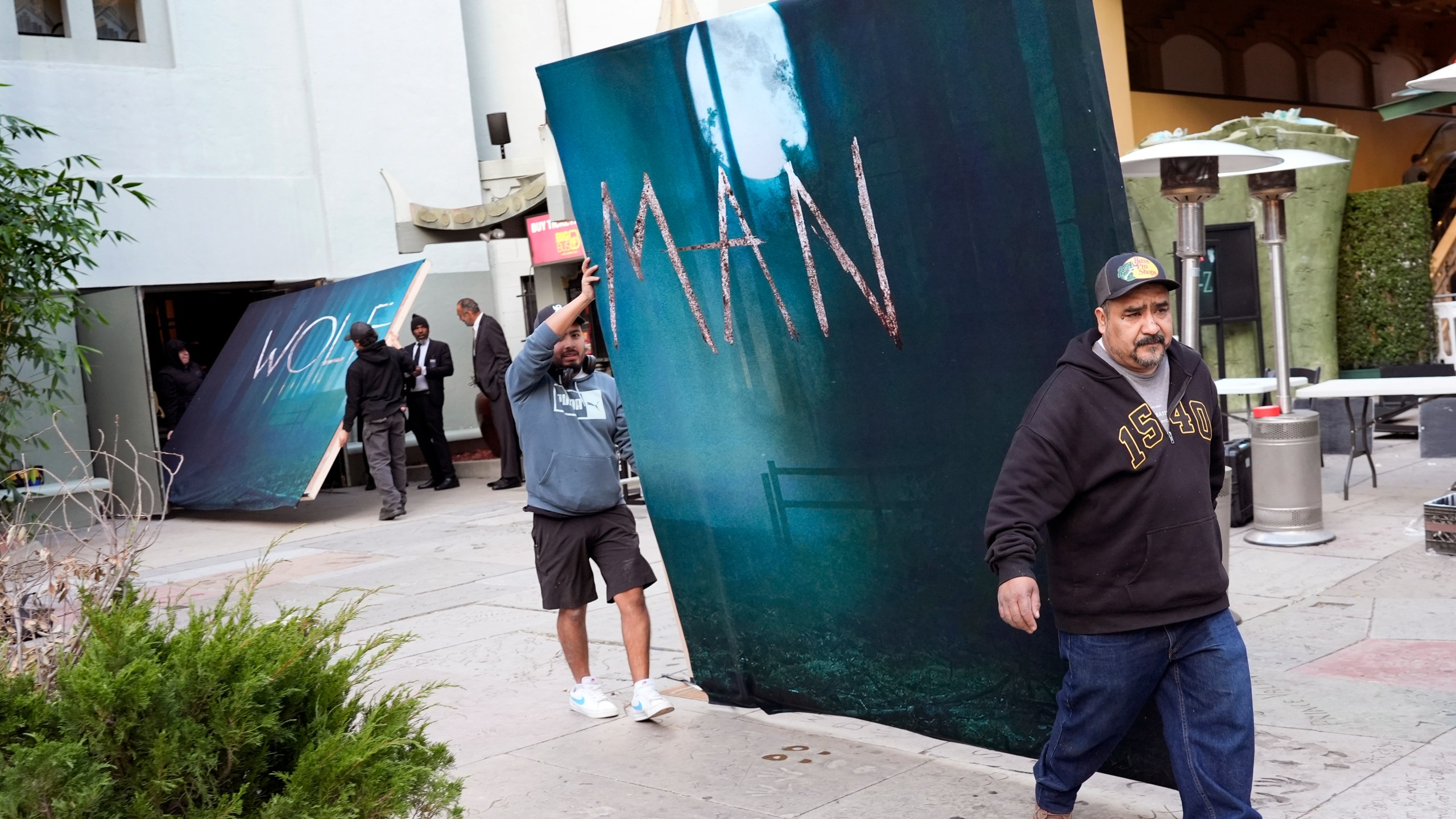 Crew members carry out signs for the new film "Wolf Man" after the premiere was cancelled due to high winds in the area on Tuesday, Jan. 7, 2025, at the TCL Chinese Theatre in Los Angeles. (AP Photo/Chris Pizzello)