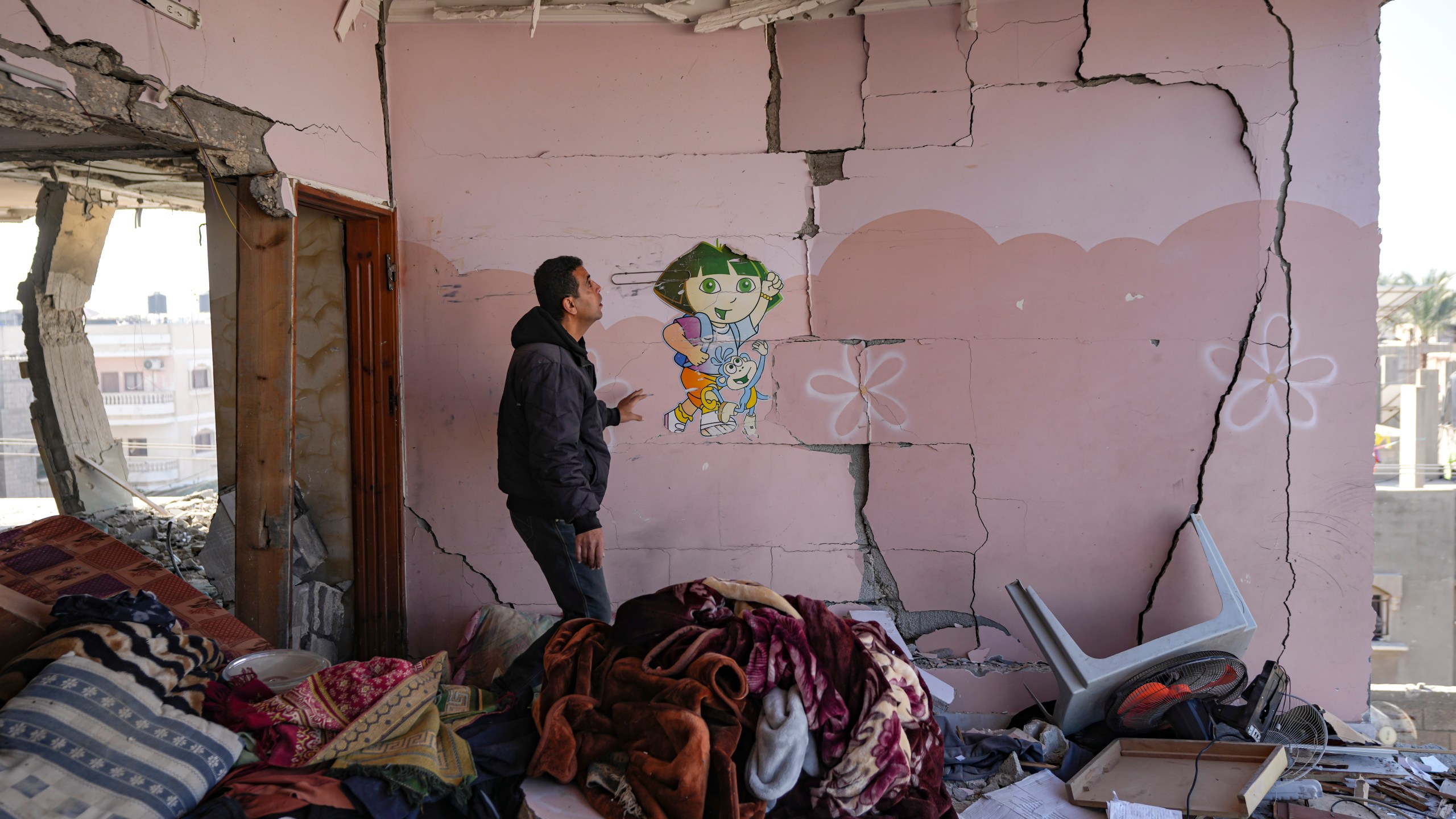 A Palestinian looks at a damaged residential building following an overnight Israeli strike in Deir al-Balah, Gaza Strip, Wednesday, Jan. 8, 2025. (AP Photo/Abdel Kareem Hana)