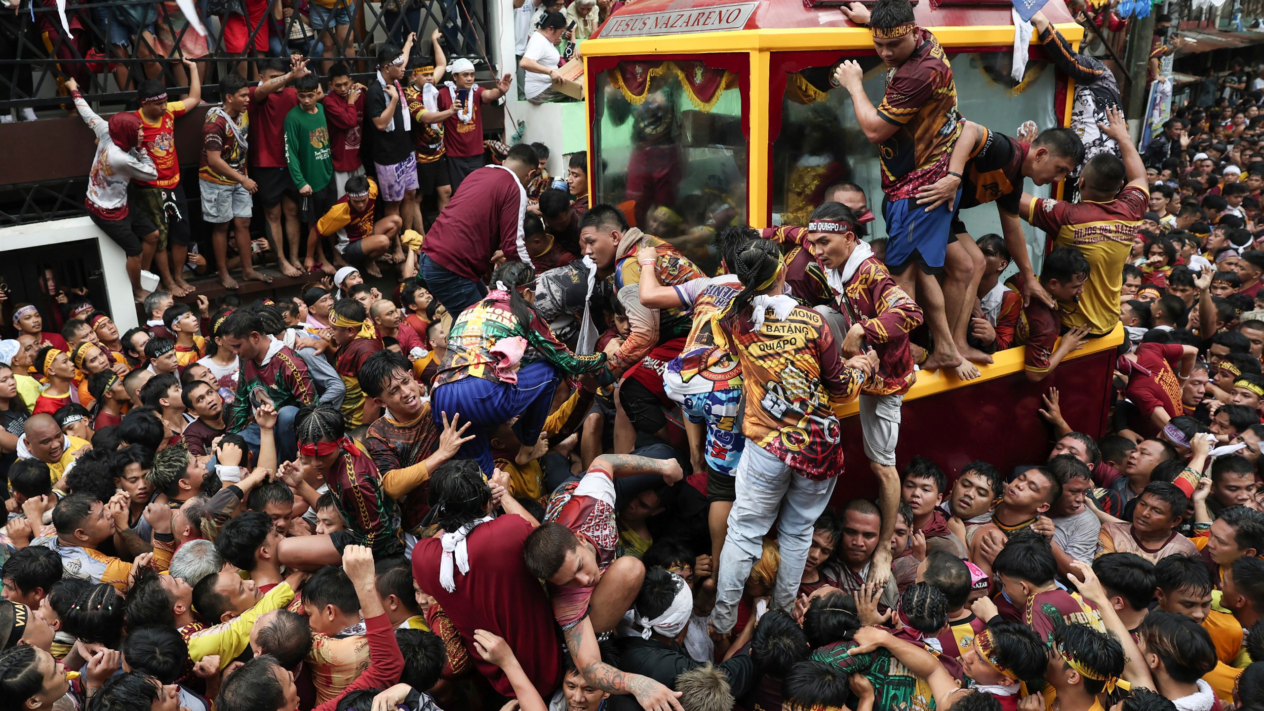 Devotees climb on a glass-covered carriage carrying the image of Jesus Nazareno during its annual procession in Manila, Philippines, Thursday, Jan. 9, 2025. (AP Photo/Basilio Sepe)