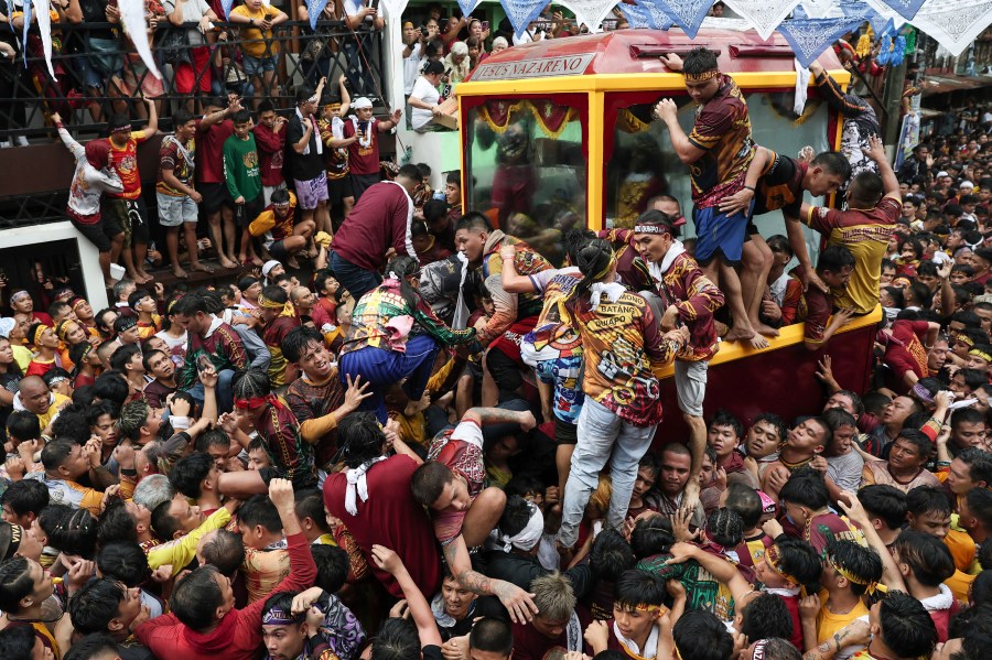 Devotees climb on a glass-covered carriage carrying the image of Jesus Nazareno during its annual procession in Manila, Philippines, Thursday, Jan. 9, 2025. (AP Photo/Basilio Sepe)