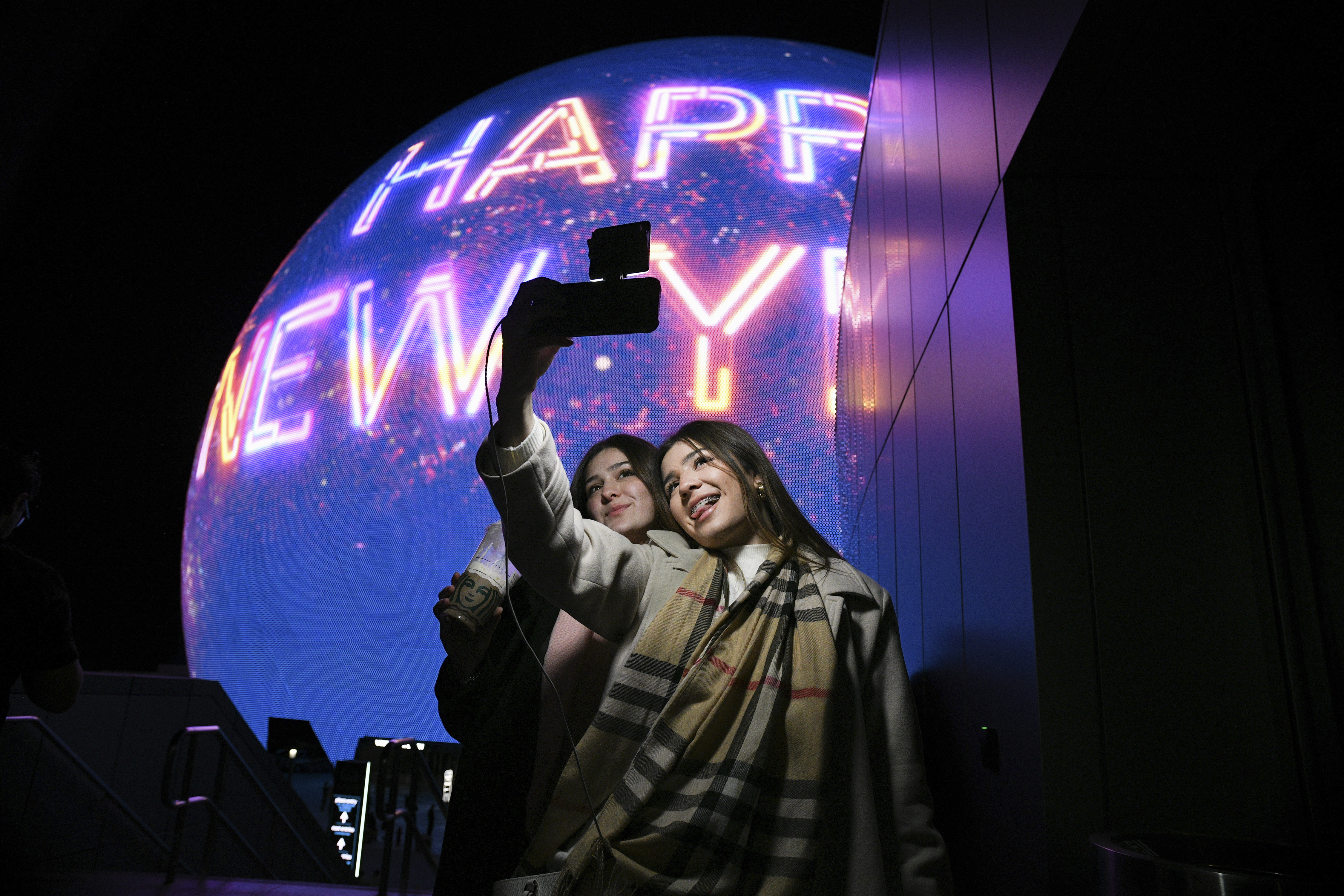 Paulina Mojica, left, and Isabelle Mojica take a selfie as the Sphere displays a Happy New Year message Tuesday, December 31, 2024, in Las Vegas. (Sam Morris/Las Vegas Review-Journal via AP)