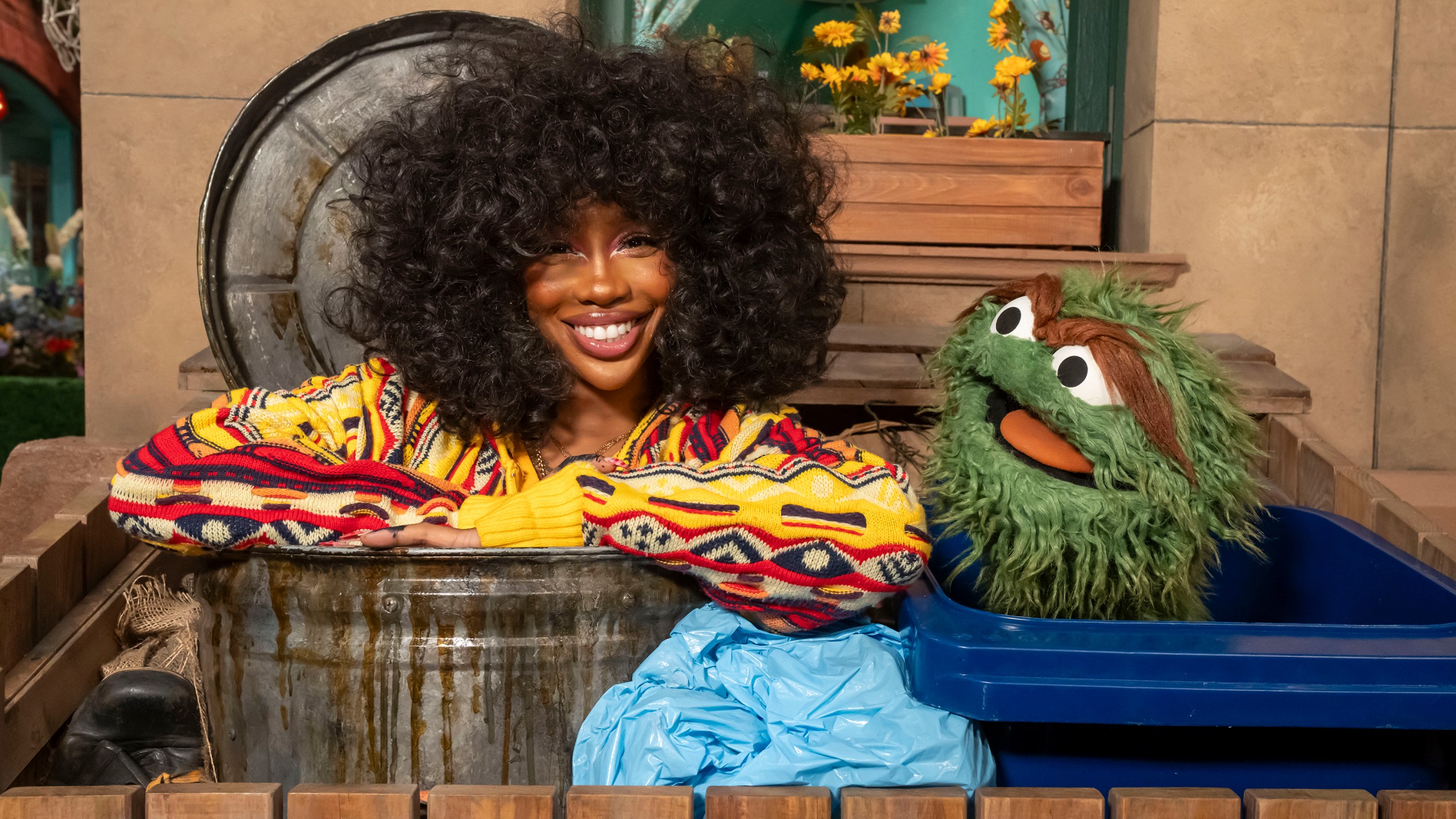 This image released by Sesame Workshop shows singer SZA, left, with muppet character Oscar the Grouch on the set of "Sesame Street." (Richard Termine/Sesame Workshop via AP)