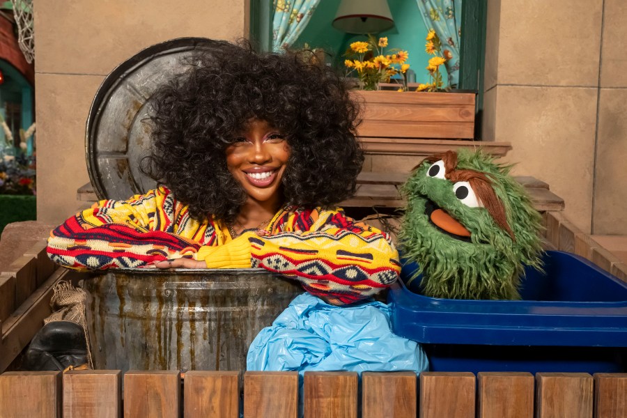 This image released by Sesame Workshop shows singer SZA, left, with muppet character Oscar the Grouch on the set of "Sesame Street." (Richard Termine/Sesame Workshop via AP)