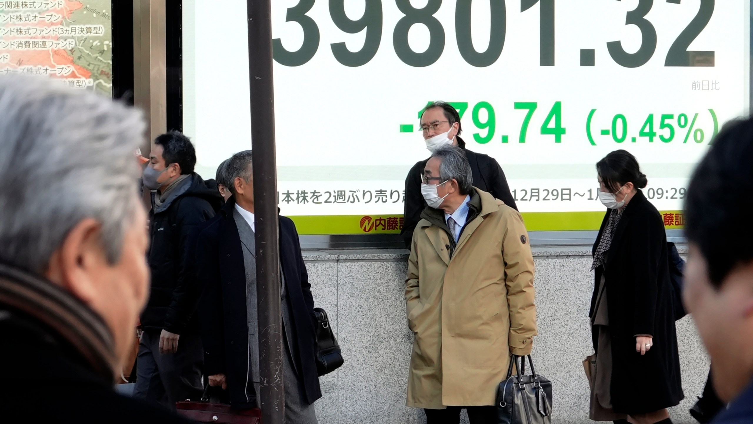 People stand near an electronic stock board showing Japan's Nikkei index at a securities firm Thursday, Jan. 9, 2025, in Tokyo. (AP Photo/Eugene Hoshiko)