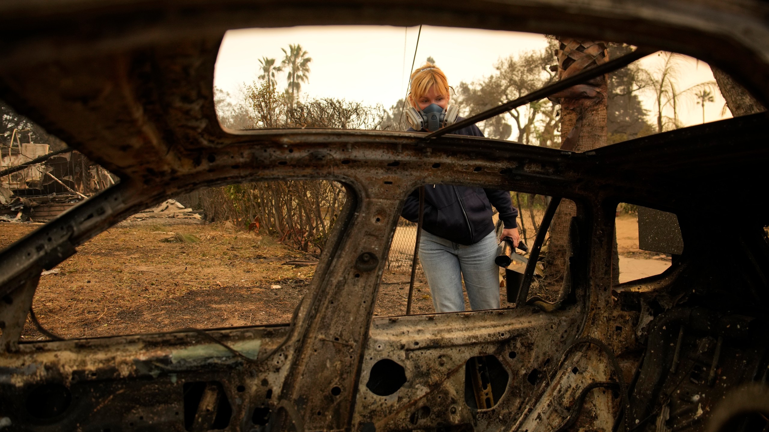 Lissa Renn looks at remains of car in Altadena, Calif., Thursday, Jan. 9, 2025. (AP Photo/John Locher)