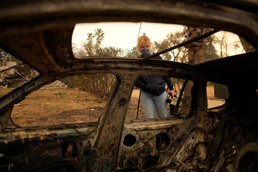 Lissa Renn looks at remains of car in Altadena, Calif., Thursday, Jan. 9, 2025. (AP Photo/John Locher)