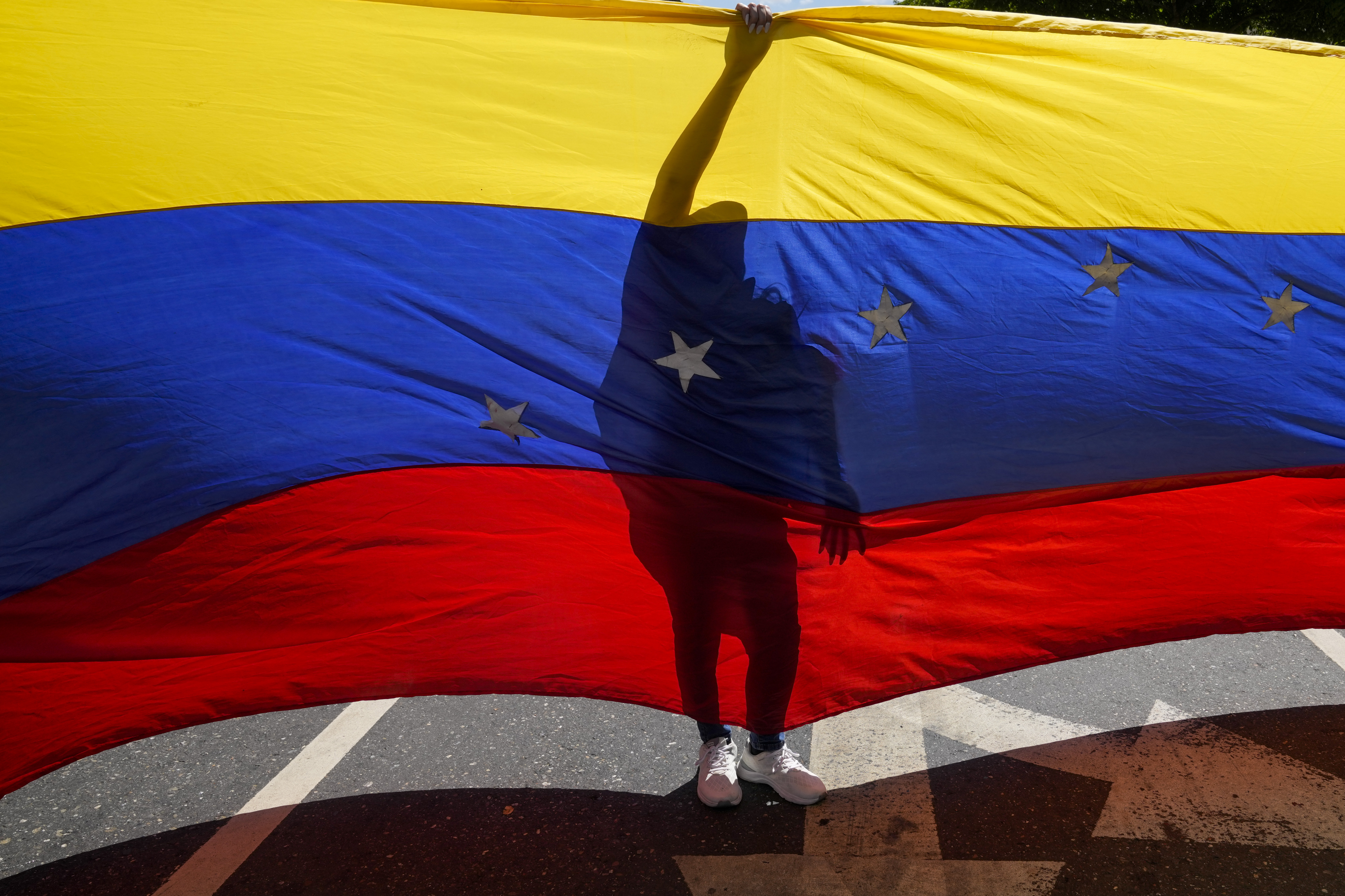 Opponents of Venezuelan President Nicolas Maduro display a Venezuelan flag during a protest the day before his inauguration for a third term in Caracas, Venezuela, Thursday, Jan. 9, 2025. (AP Photo/Ariana Cubillos)