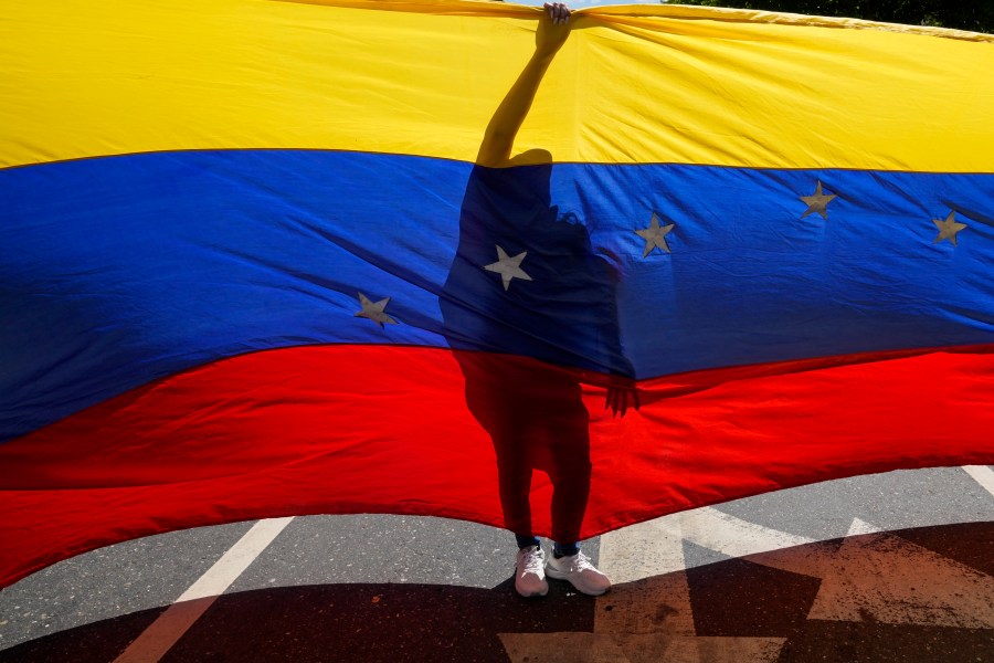 Opponents of Venezuelan President Nicolas Maduro display a Venezuelan flag during a protest the day before his inauguration for a third term in Caracas, Venezuela, Thursday, Jan. 9, 2025. (AP Photo/Ariana Cubillos)