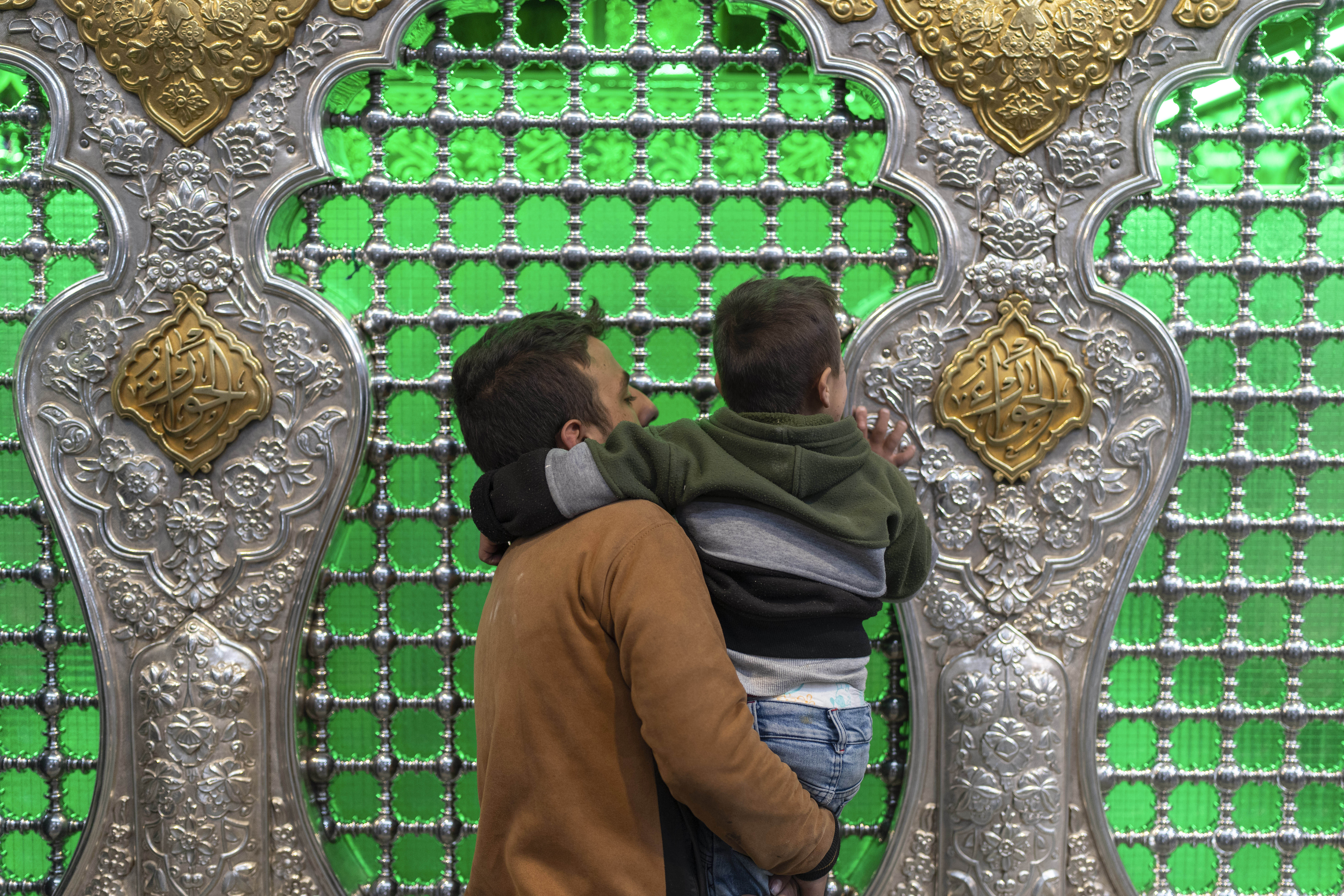 A man carries his child as they pray at the shrine of Sayyida Zaynab, the granddaughter of Prophet Mohammad, in Damascus, Syria, Saturday, Jan. 11, 2025. (AP Photo/Mosa'ab Elshamy)