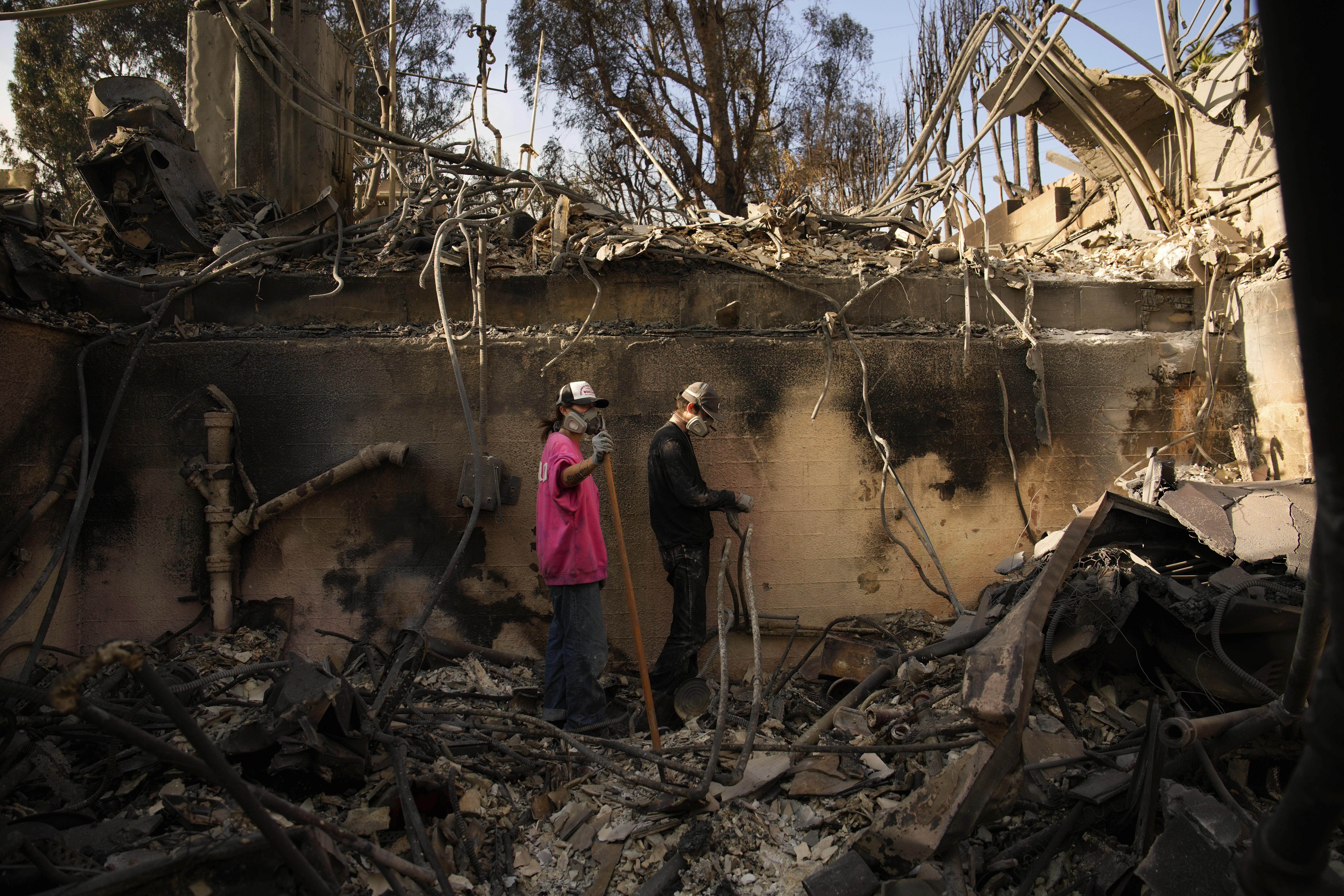 Kaegan Baron, left, and Oliver Braren sift through the home of Kaegan's mother after it was destroyed by the Palisades Fire in the Pacific Palisades neighborhood of Los Angeles, Saturday, Jan. 11, 2025. (AP Photo/John Locher)