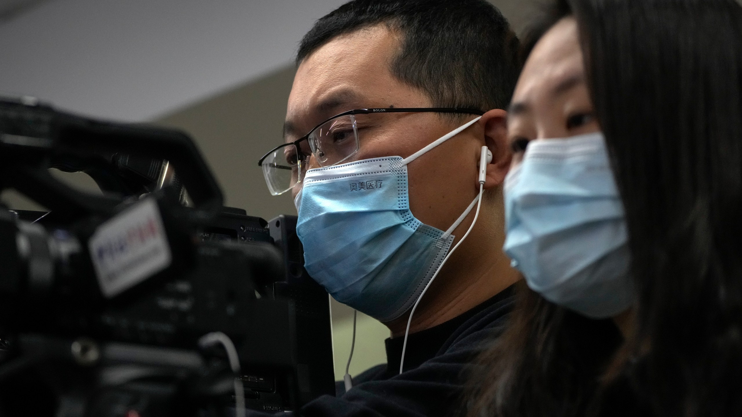 Journalists wearing face masks film a speech of Wang Liping, a researcher for the Chinese Center for Disease Control and Prevention during a press briefing by the National Health Commission in Beijing, Sunday, Jan. 12, 2025. (AP Photo/Andy Wong)