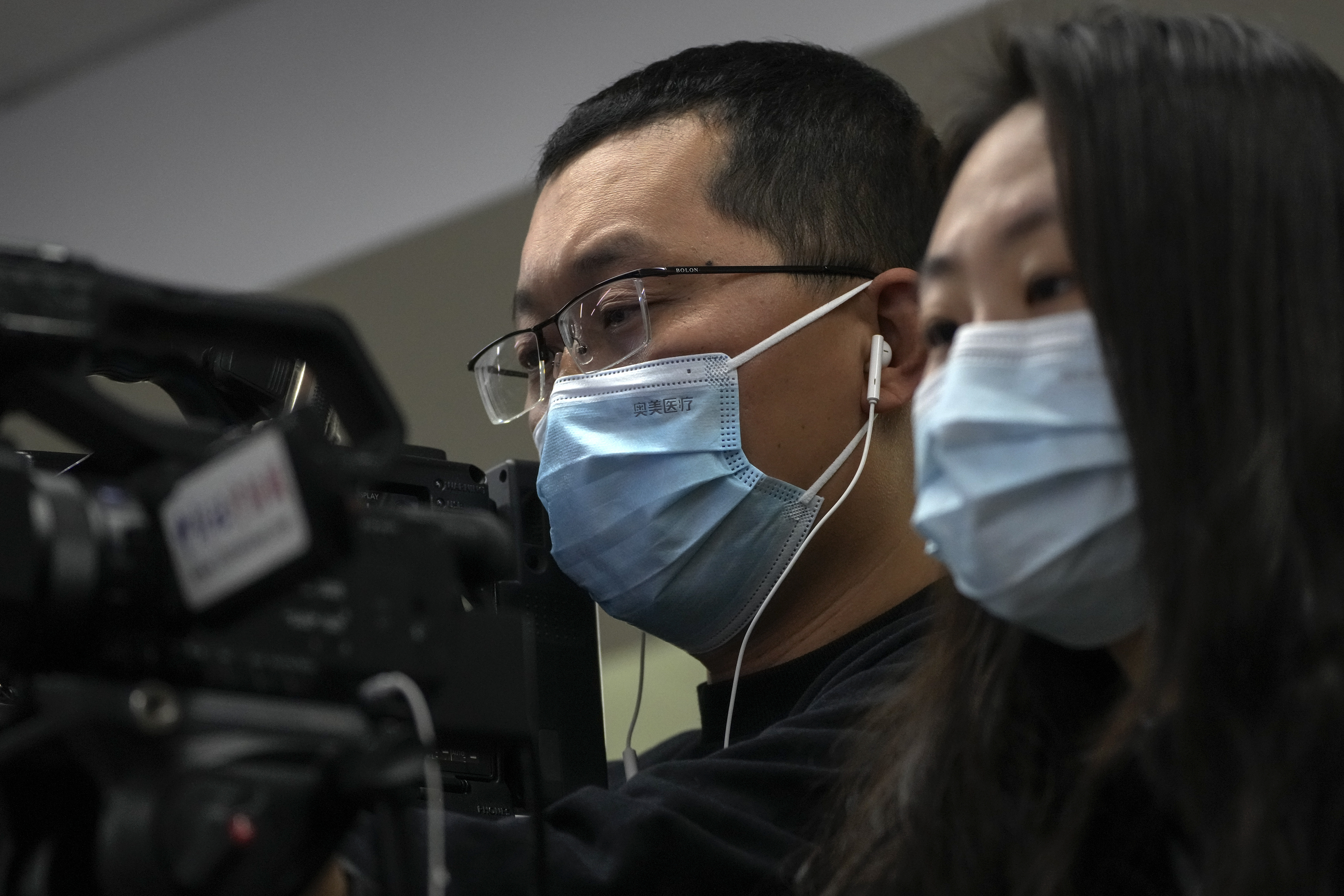 Journalists wearing face masks film a speech of Wang Liping, a researcher for the Chinese Center for Disease Control and Prevention during a press briefing by the National Health Commission in Beijing, Sunday, Jan. 12, 2025. (AP Photo/Andy Wong)