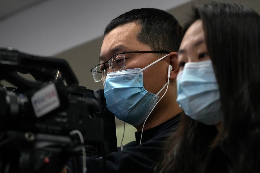 Journalists wearing face masks film a speech of Wang Liping, a researcher for the Chinese Center for Disease Control and Prevention during a press briefing by the National Health Commission in Beijing, Sunday, Jan. 12, 2025. (AP Photo/Andy Wong)