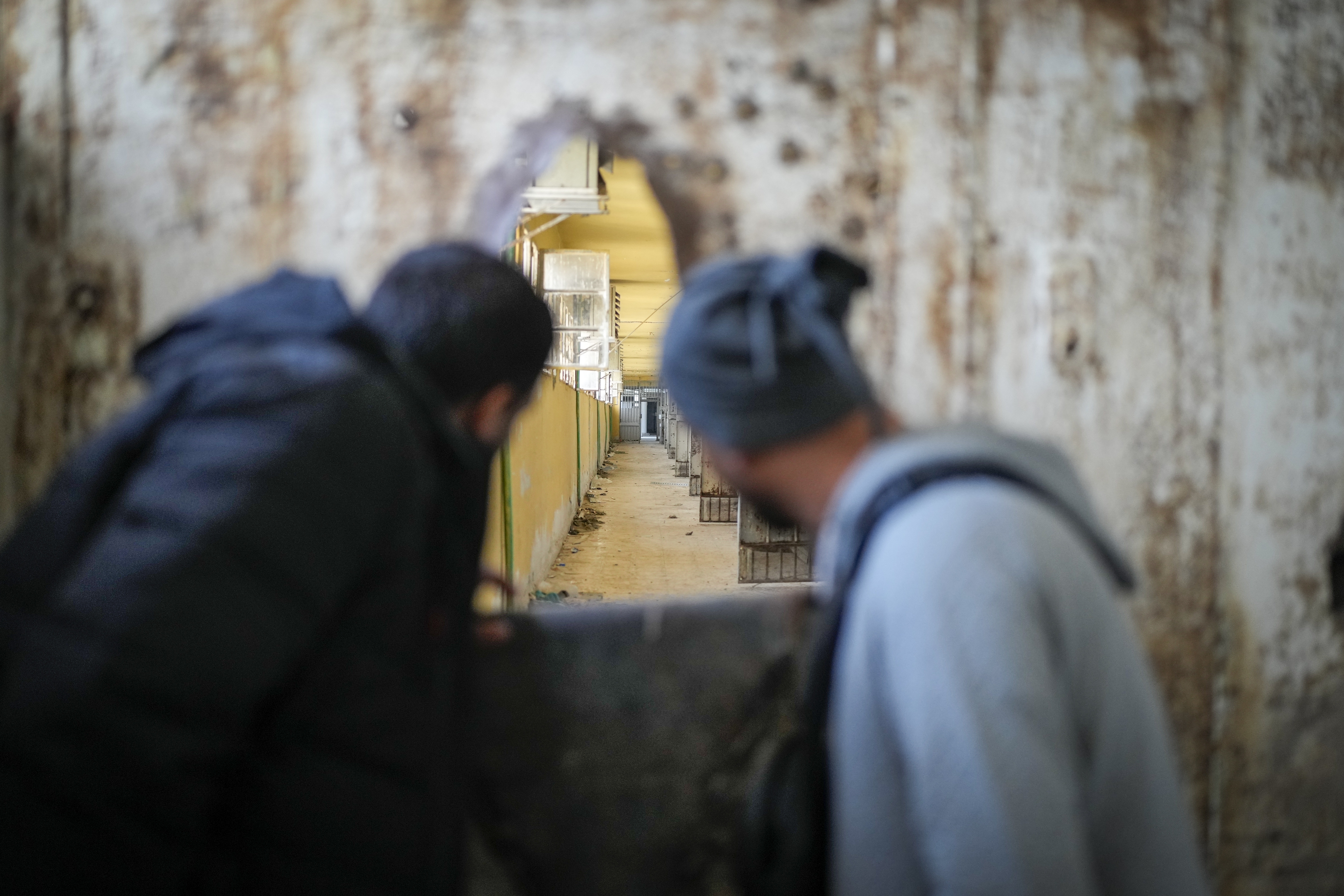 People peer through a hole in the wall into the cells gallery of the infamous Saydnaya military prison on the outskirts of Damascus, Syria, Sunday Jan. 12, 2025. (AP Photo/Mosa'ab Elshamy)