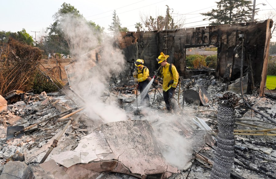 Firefighters extinguish burning embers at a house on Santa Rosa Avenue, also known as Christmas Tree Lane, after the house was destroyed by the Eaton Fire, Thursday, Jan. 9, 2025, in Altadena, Calif. (AP Photo/Chris Pizzello)