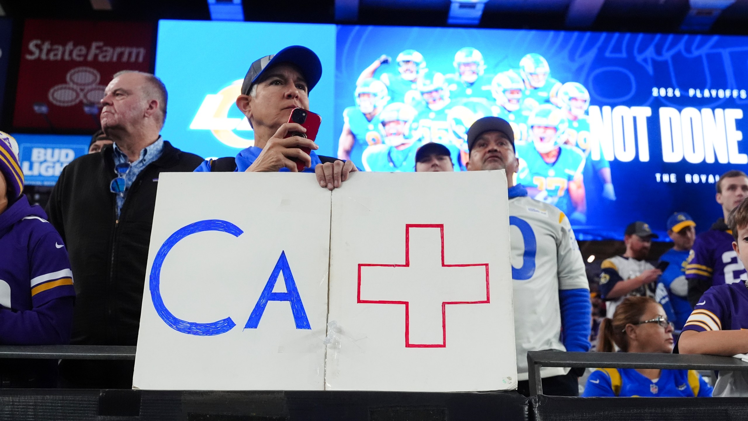 A Los Angeles Rams fan holds a sign b before an NFL wild card playoff football game against the Minnesota Vikings, Monday, Jan. 13, 2025, in Glendale, Ariz. (AP Photo/Ross D. Franklin)