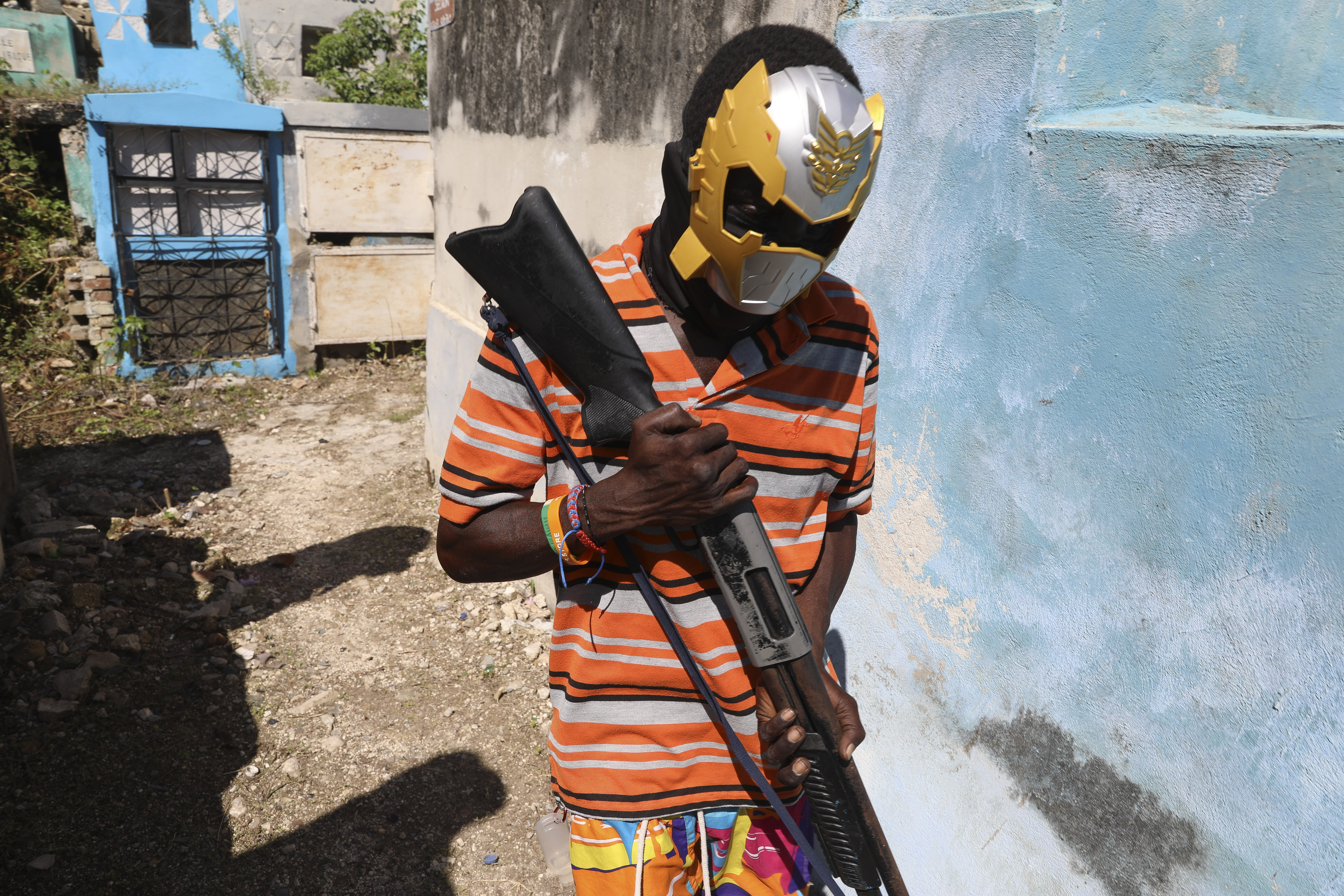 A masked, armed gang member poses for a photo at the National Cemetery during the Fete Gede festival celebrating Day of the Dead to honor the Haitian Vodou spirits Baron Samedi and Gede in Port-au-Prince, Haiti, Nov. 1, 2024. (AP Photo/Odelyn Joseph)