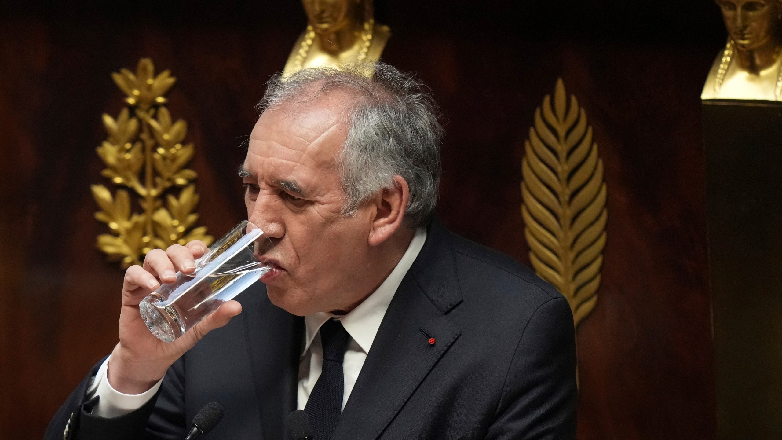 French Prime Minister Francois Bayrou drinks as he delivers his general policy speech, Tuesday, Jan. 14, 2025 at the National Assembly in Paris. (AP Photo/Thibault Camus)