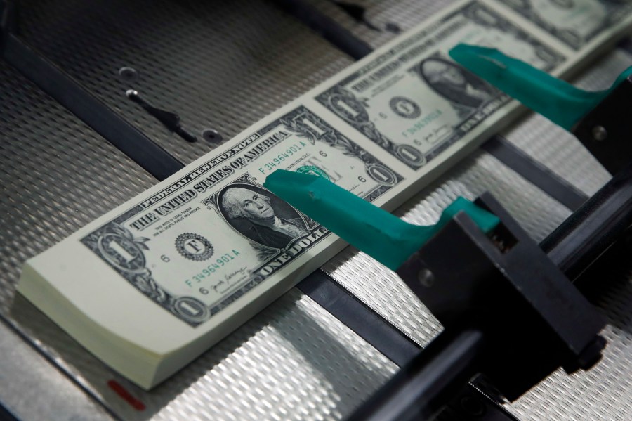 FILE- In this Nov. 15, 2017, file photo, new $1 bills are cut and stacked at the Bureau of Engraving and Printing in Washington. (AP Photo/Jacquelyn Martin, File)