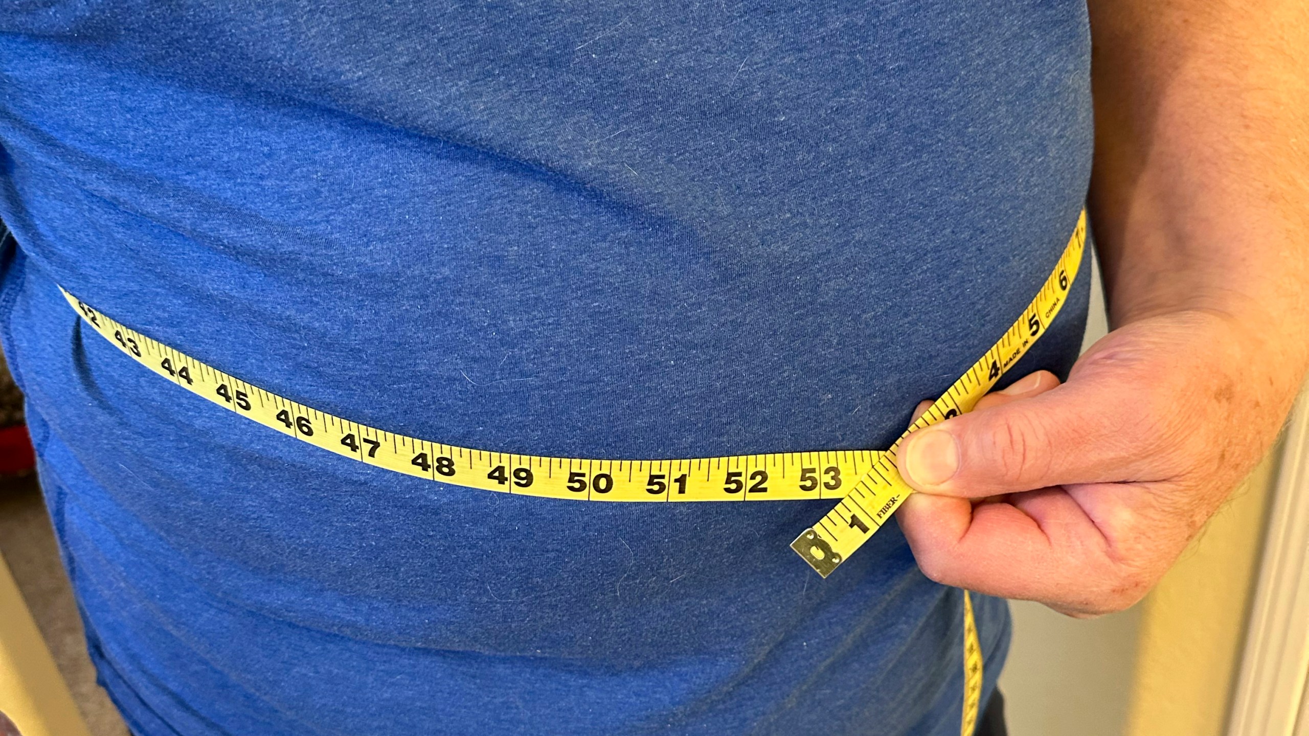 A man uses measuring tape on his waist in California on Jan. 9, 2025. (AP Photo/JoNel Aleccia)