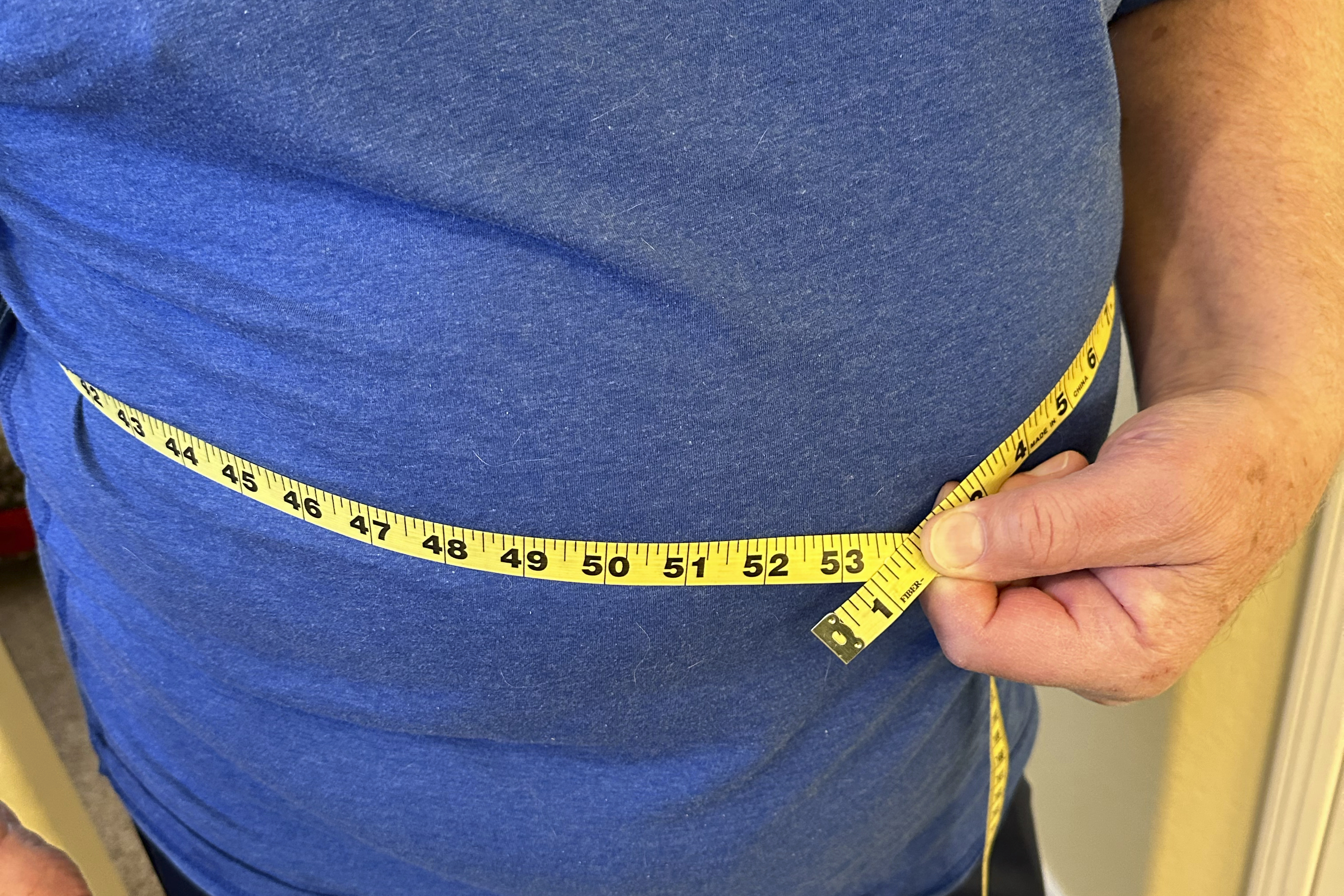 A man uses measuring tape on his waist in California on Jan. 9, 2025. (AP Photo/JoNel Aleccia)