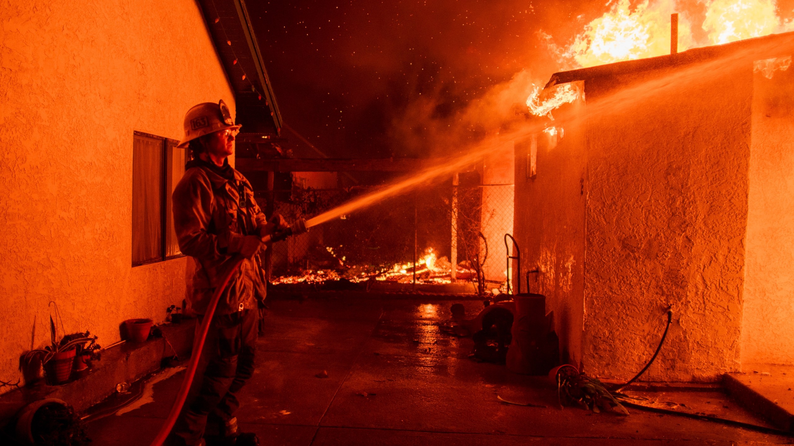 FILE - A firefighter sprays water on a garage burning in the Eaton Fire in Altadena, Calif., Jan. 8, 2025. (AP Photo/Nic Coury, File)