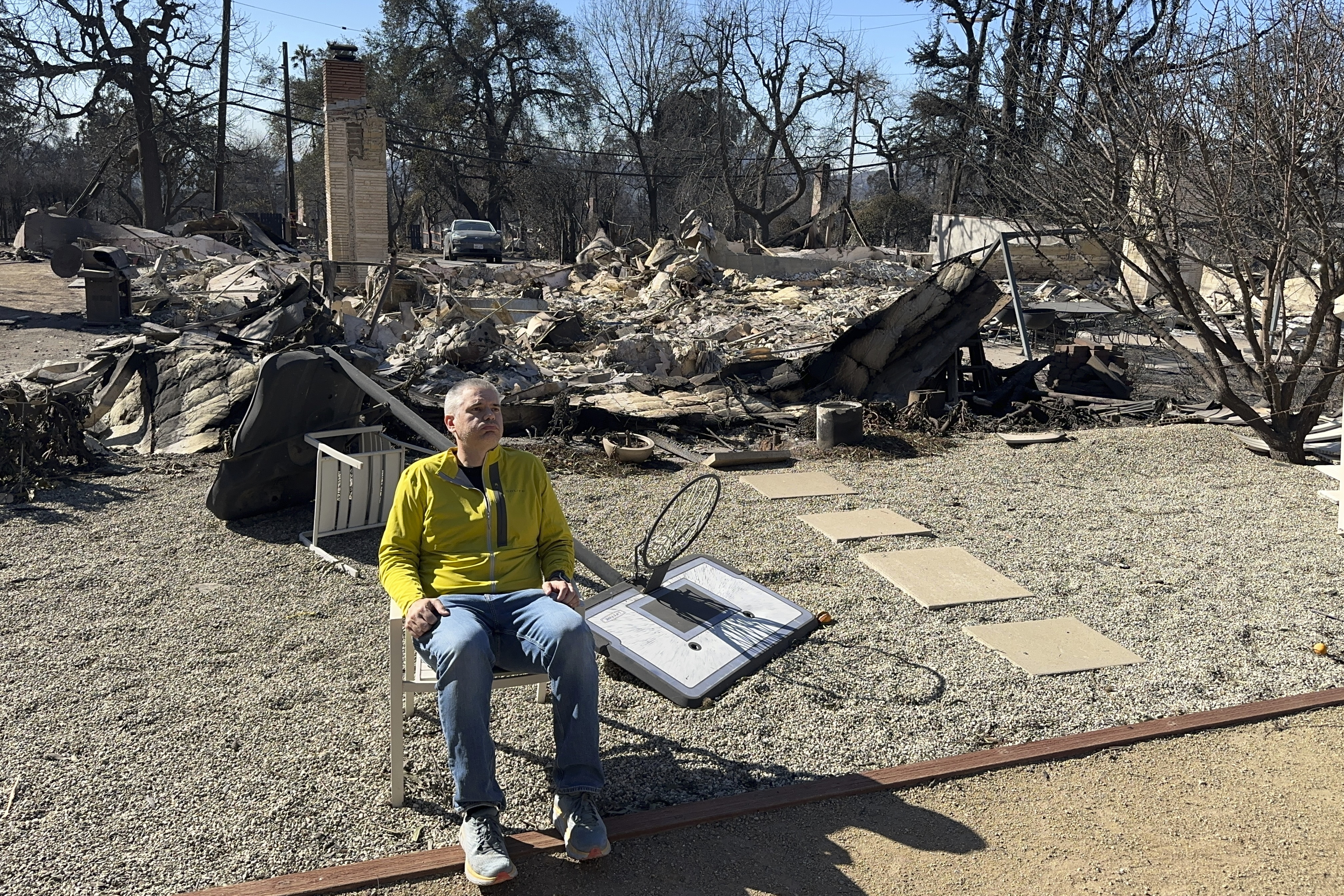 Ryan Pearson, a Los Angeles-based entertainment video editor for The Associated Press, sits in front of his home that was destroyed by the Eaton Fire in Altadena, Calif., Wednesday, Jan. 15, 2025. (AP Photo/Ryan Pearson)