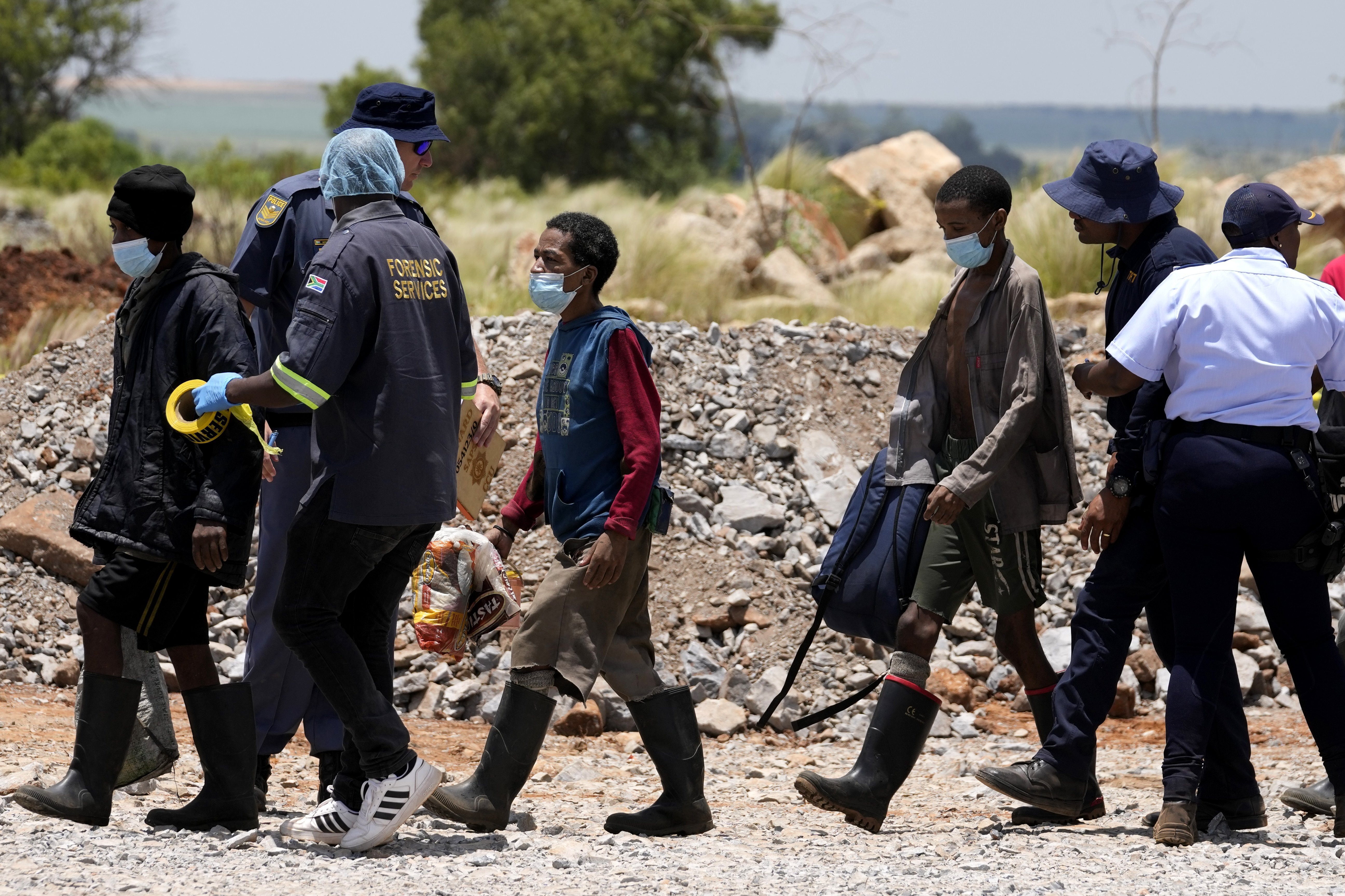 Illegal miners are escorted by police officers after being rescued from an abandoned gold mine for months, in Stilfontein, South Africa, Tuesday, Jan. 14, 2025. (AP Photo/Themba Hadebe)