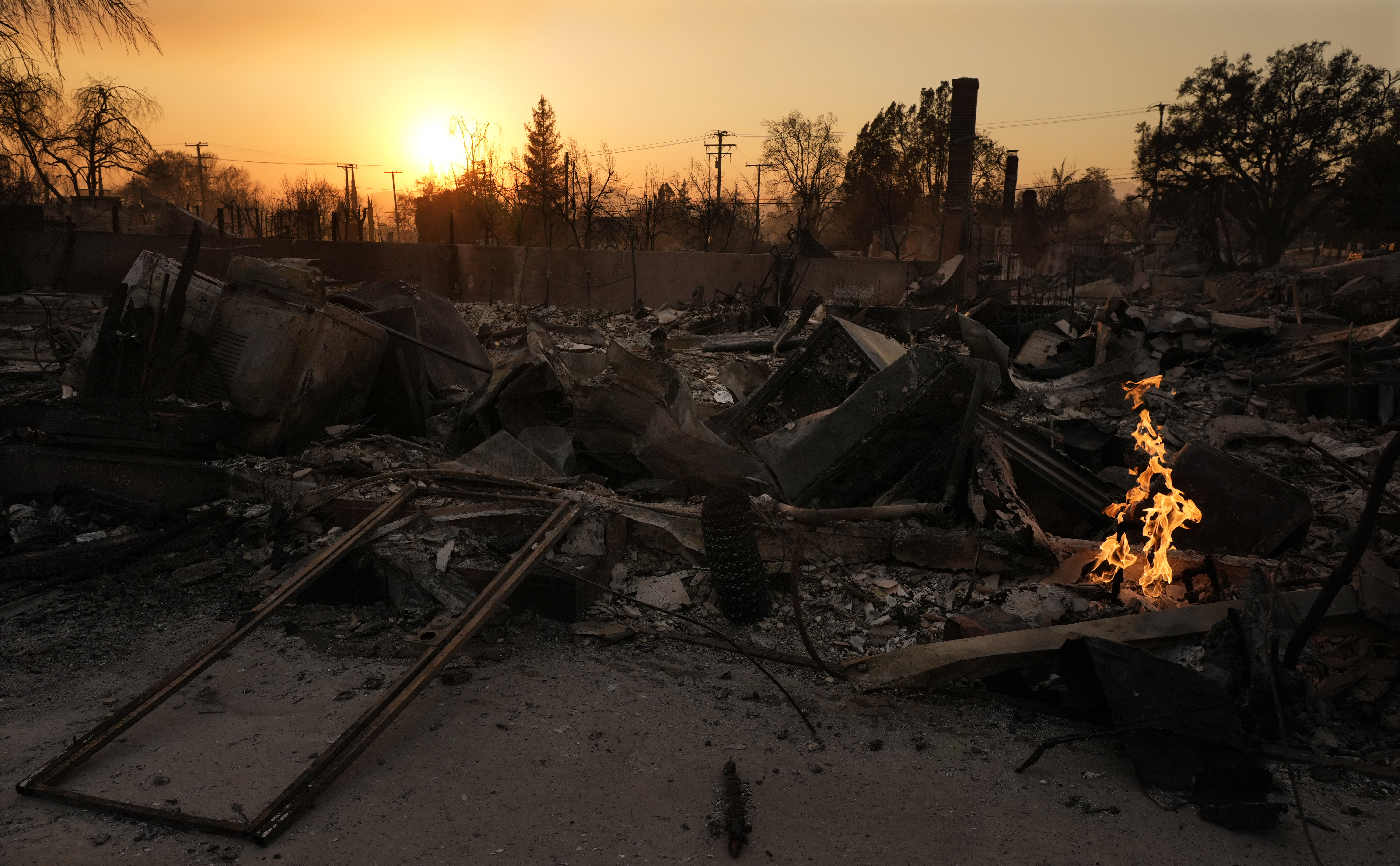 FILE - A small fire burns on the ruins of a house after it was destroyed by the Eaton Fire, Jan. 9, 2025, in Altadena, Calif. (AP Photo/Chris Pizzello, File)