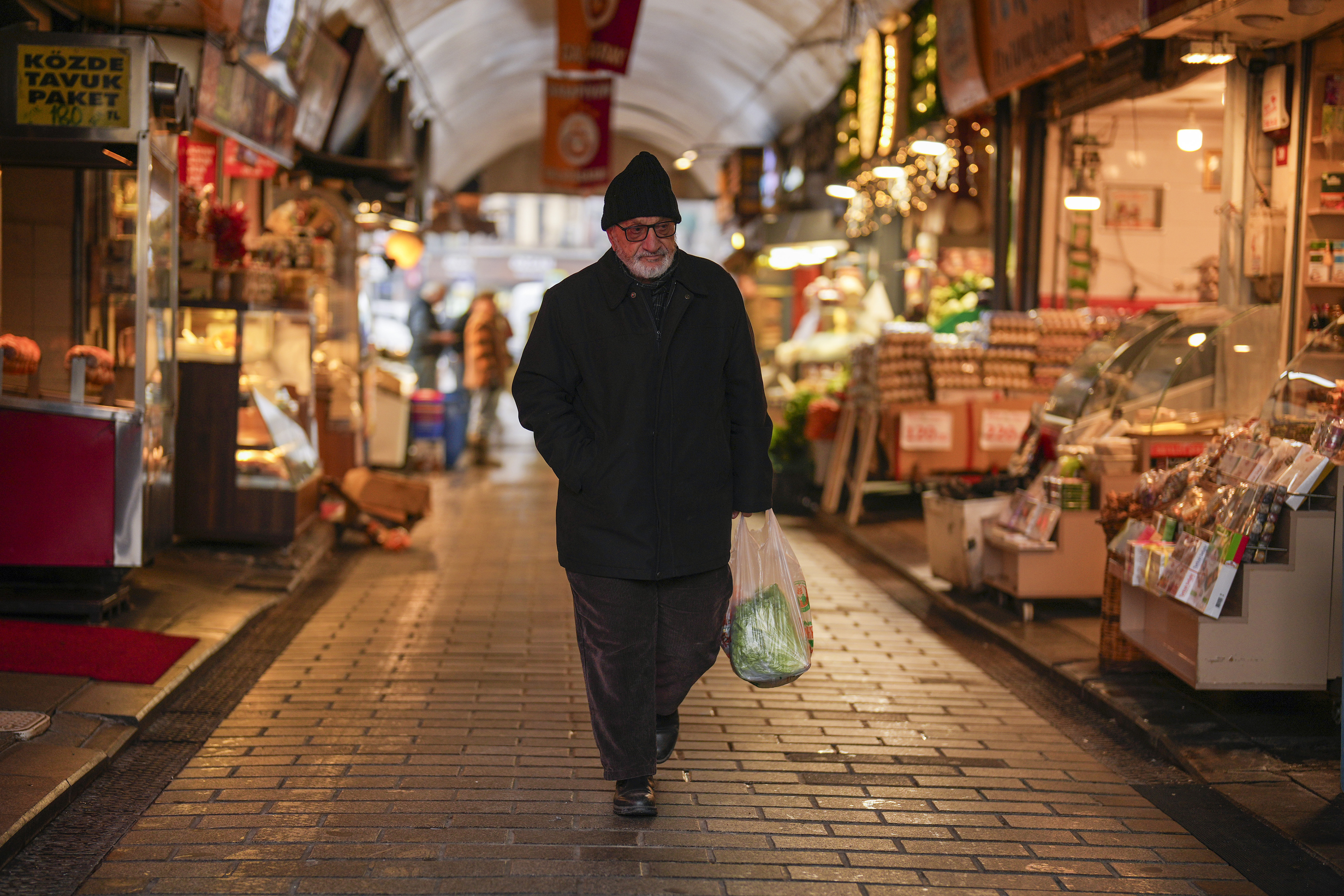 A man carries a bag with groceries in a food street market at Uskudar neighbourhood in Istanbul, Turkey, Thursday, Jan. 23, 2025, same day as Turkey's central bank lowered its key interest rate by 2.5 percentage points to 45%. (AP Photo/Francisco Seco)