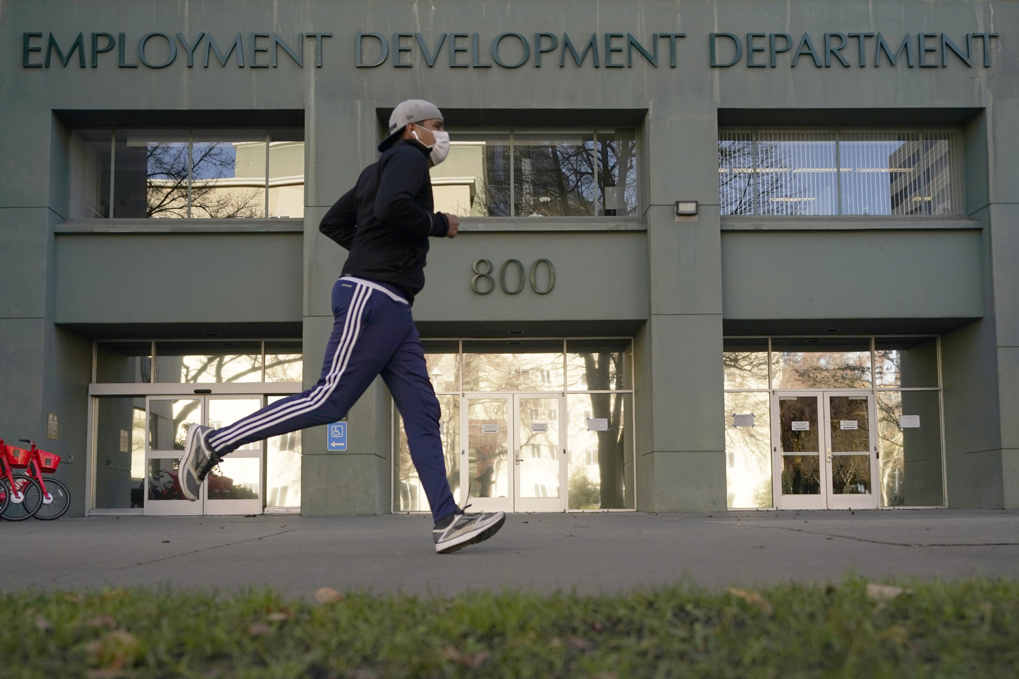 FILE - In this Dec. 18, 2020, file photo a runner passes the office of the California Employment Development Department in Sacramento, Calif. (AP Photo/Rich Pedroncelli, File)