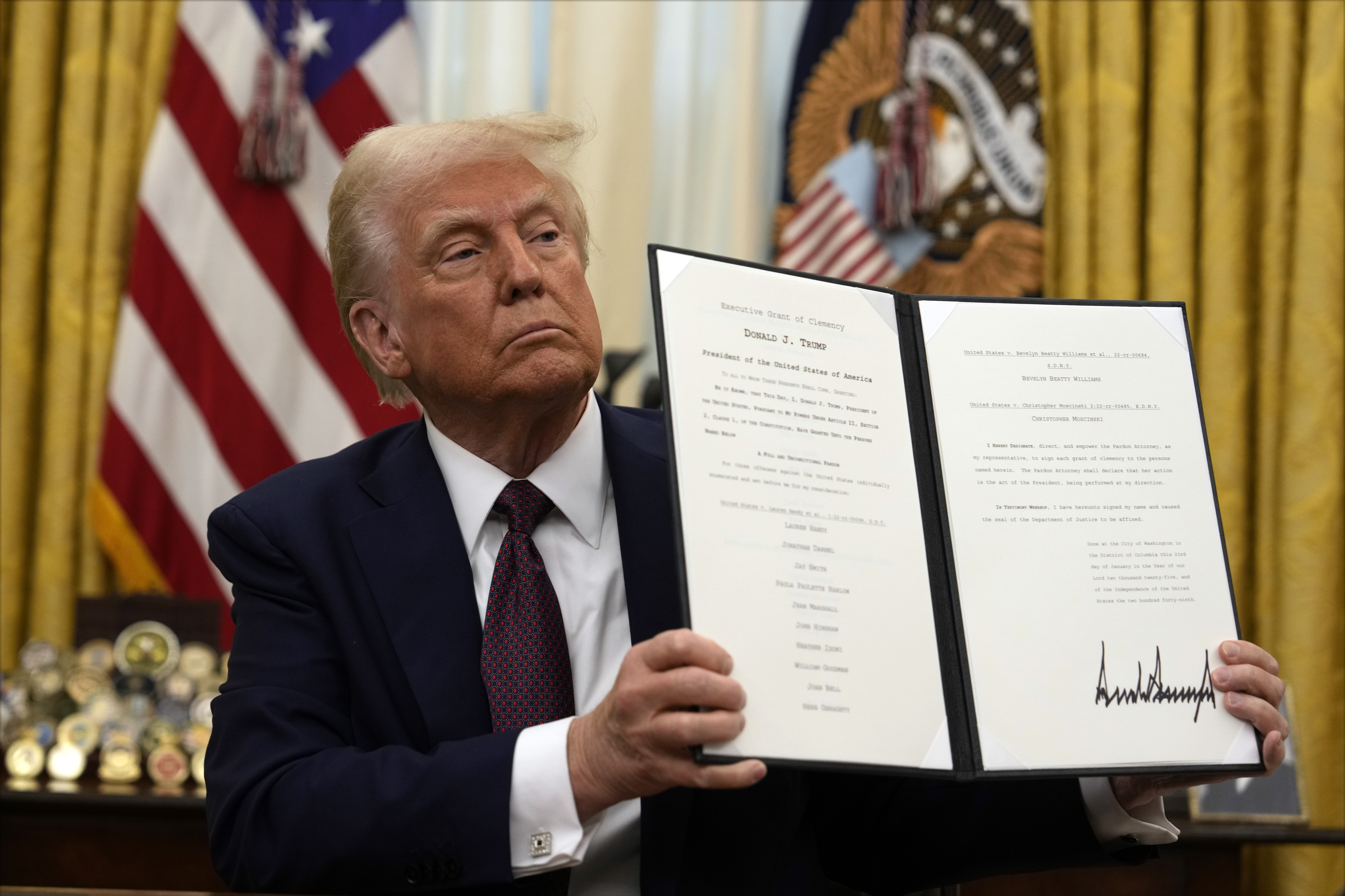 President Donald Trump holding up a order for clemency for anti-abortion protesters as he signs executive orders in the Oval Office of the White House, Thursday, Jan. 23, 2025, in Washington. (AP Photo/Ben Curtis)