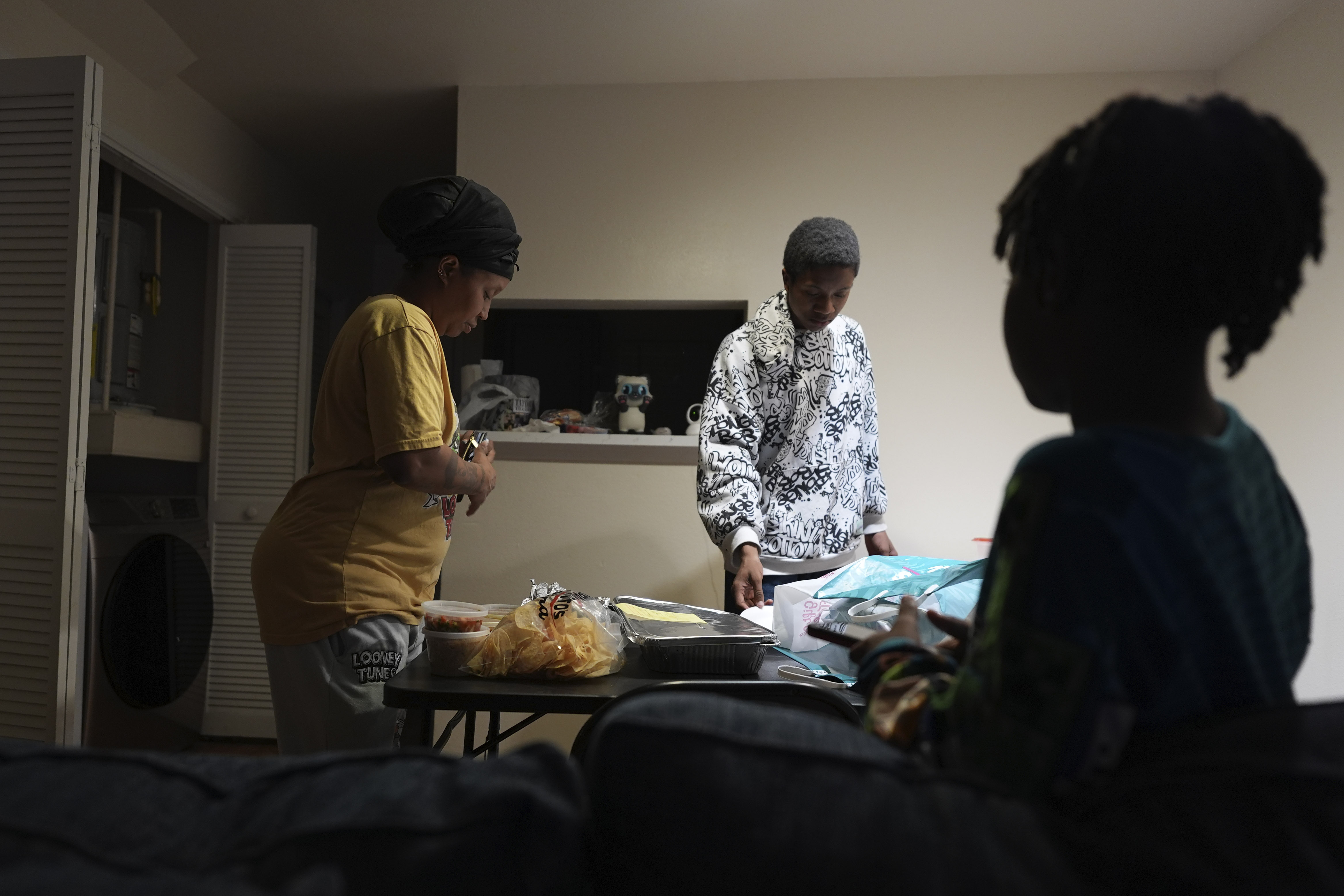 TiAnna Yeldell, with her sons Marq'ue, center, and Ivan, right, sets out dinner at her home, Thursday, Nov. 14, 2024, in Missouri City, Texas. (AP Photo/Eric Gay)