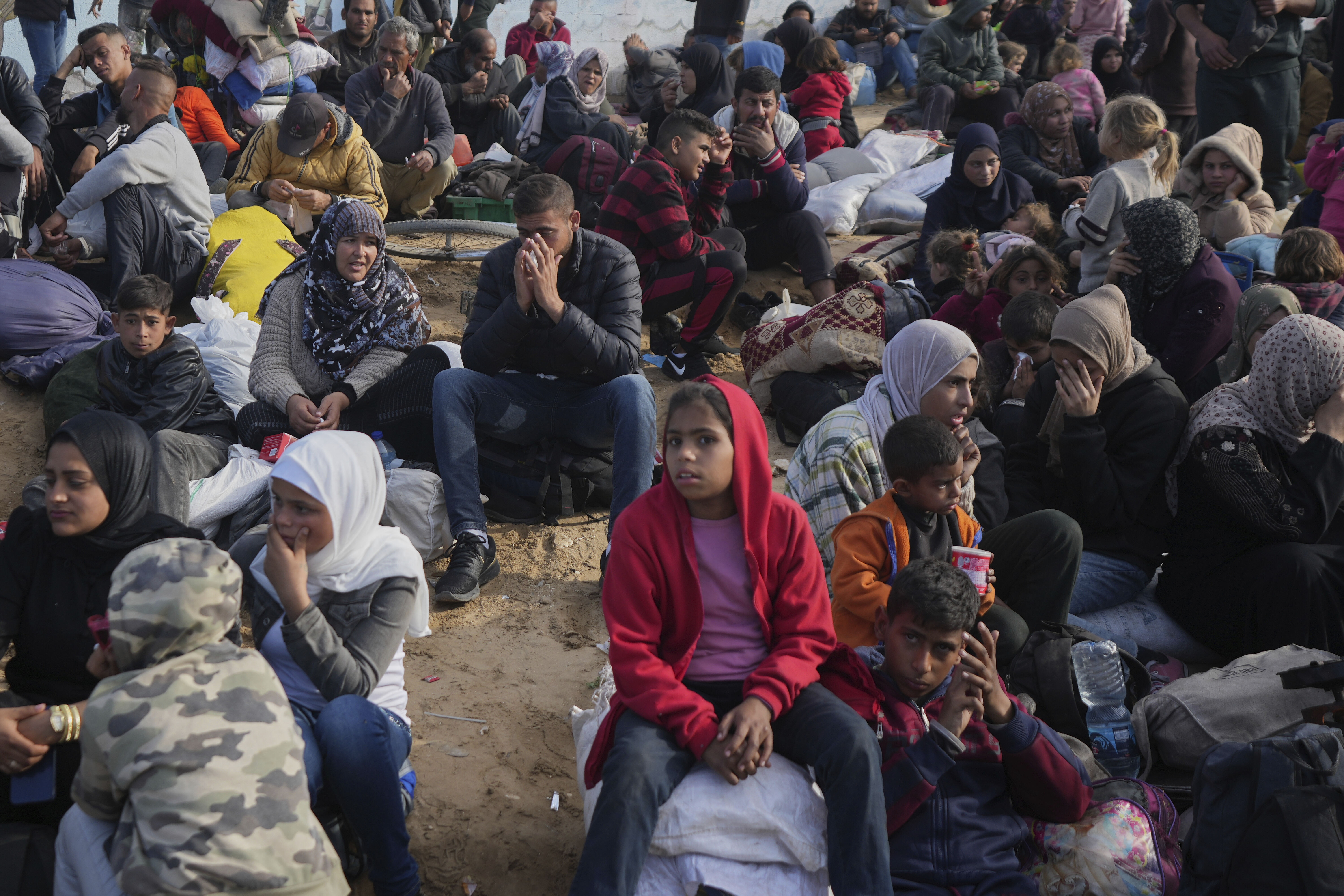 Palestinians wait next to their belongings in central Gaza, Saturday, Jan. 25, 2025, as the Israeli military is warning Palestinians not to return to northern Gaza. (AP Photo/Abdel Kareem Hana)