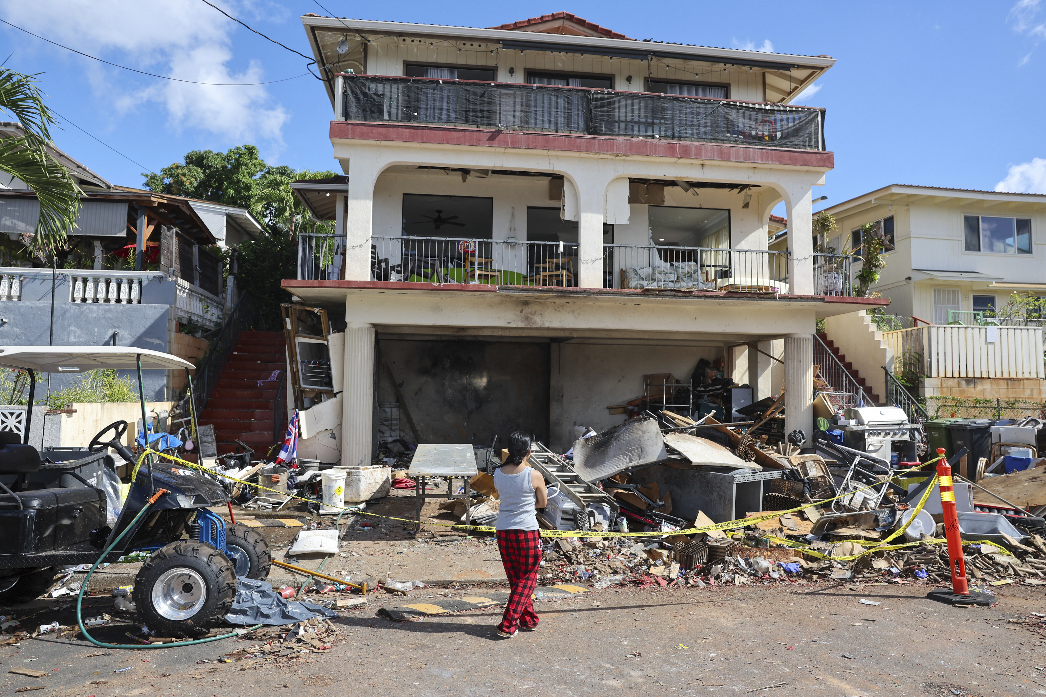 FILE - A woman stands in front of the home where a New Year's Eve fireworks explosion killed and injured people, Jan. 1, 2025, in Honolulu. (AP Photo/Marco Garcia, file)