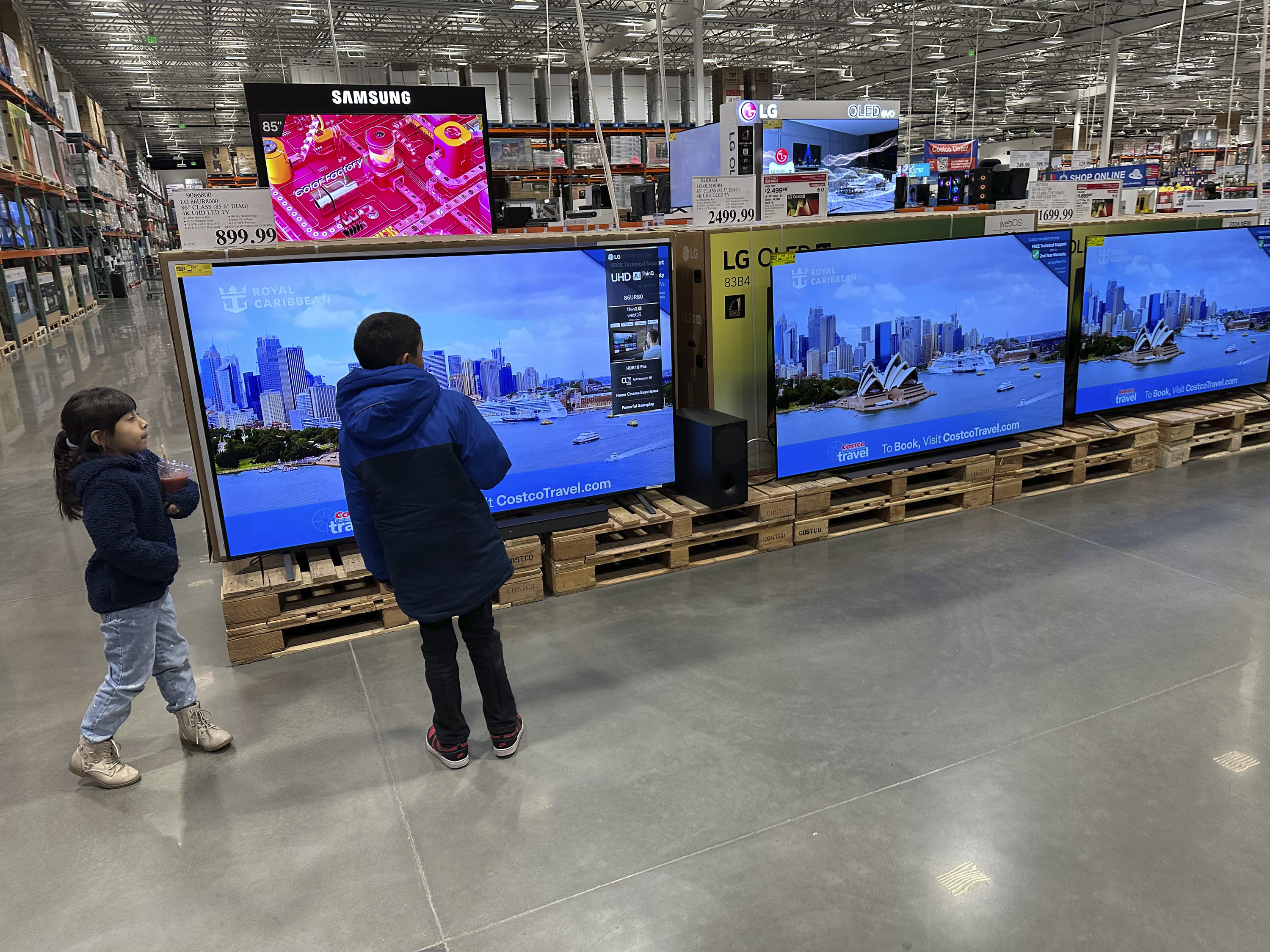 Young shoppers look over a row of large-screen televisions on display in a Costco warehouse Thursday, Dec. 19, 2024, in Denver. (AP Photo/David Zalubowski)