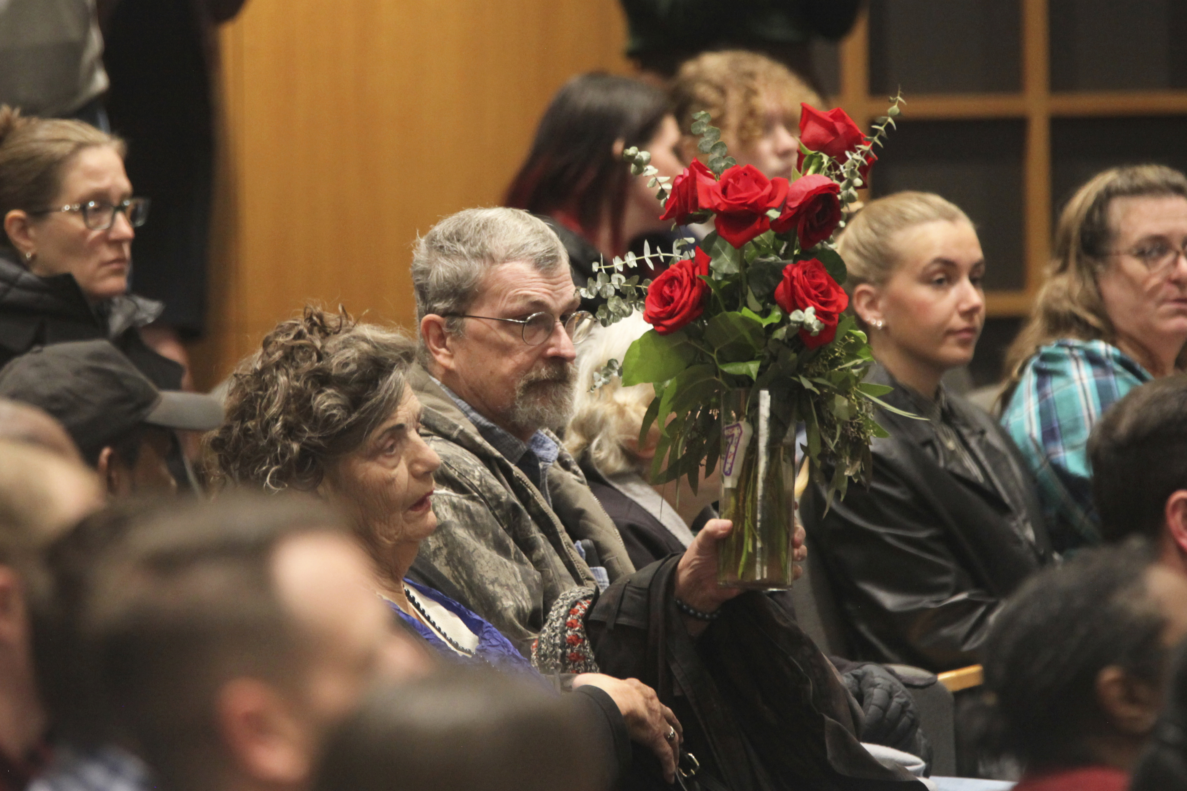 Carla Lee, a retired Wichita State University nursing professor, holds up a vase of red roses to show her support for the families of victims of a deadly collision between a passenger airliner and an Army helicopter that occurred the day prior, Thursday, Jan. 30, 2025, during a prayer vigil in Wichita, Kan., where the airline passenger flight originated. (AP Photo/John Hanna)