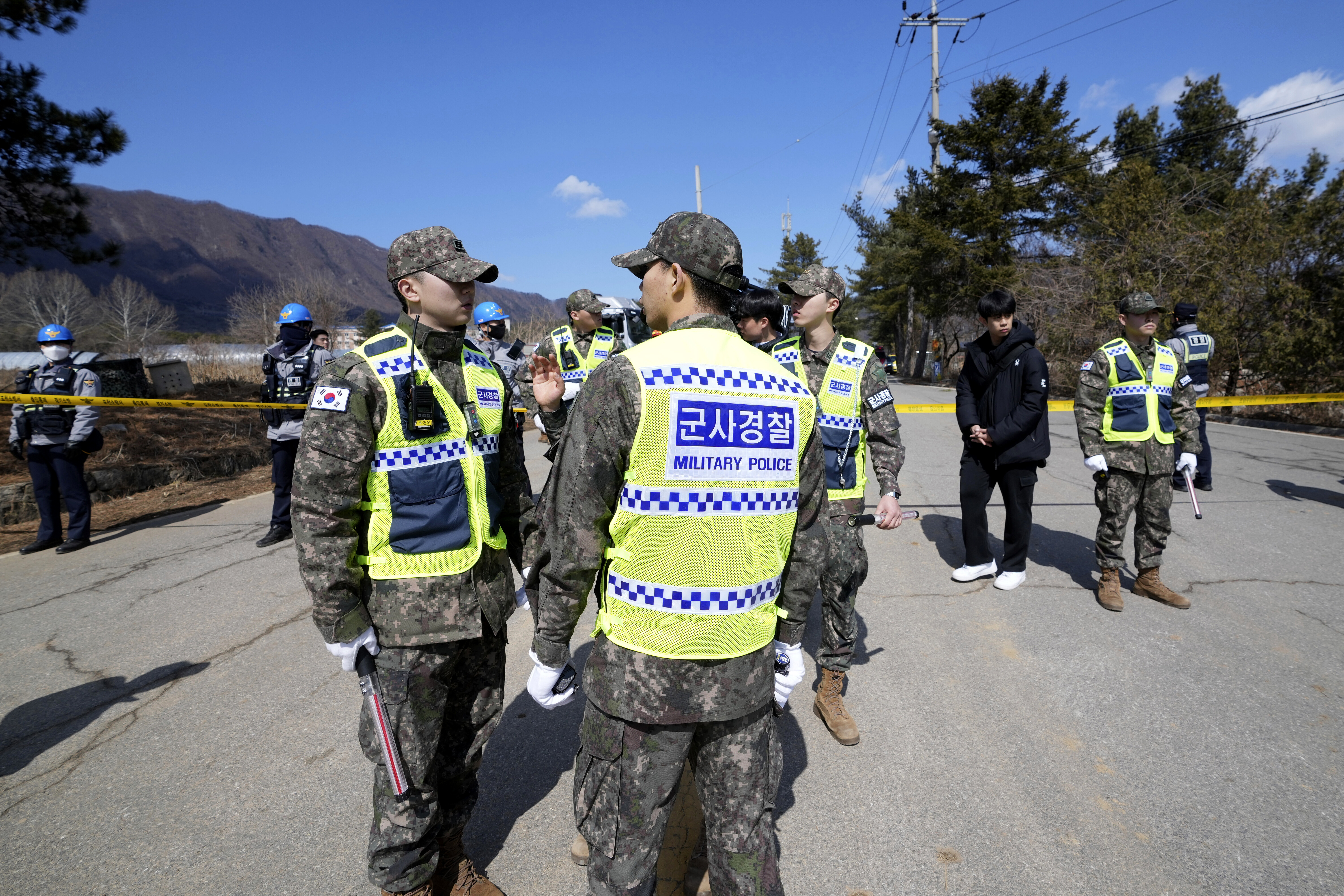 South Korean soldiers and police officers stand near the scene where a South Korean fighter jet accidentally dropped bombs on a civilian area during training, in Pocheon, South Korea, Thursday, March 6, 2025. (AP Photo/Lee Jin-man)