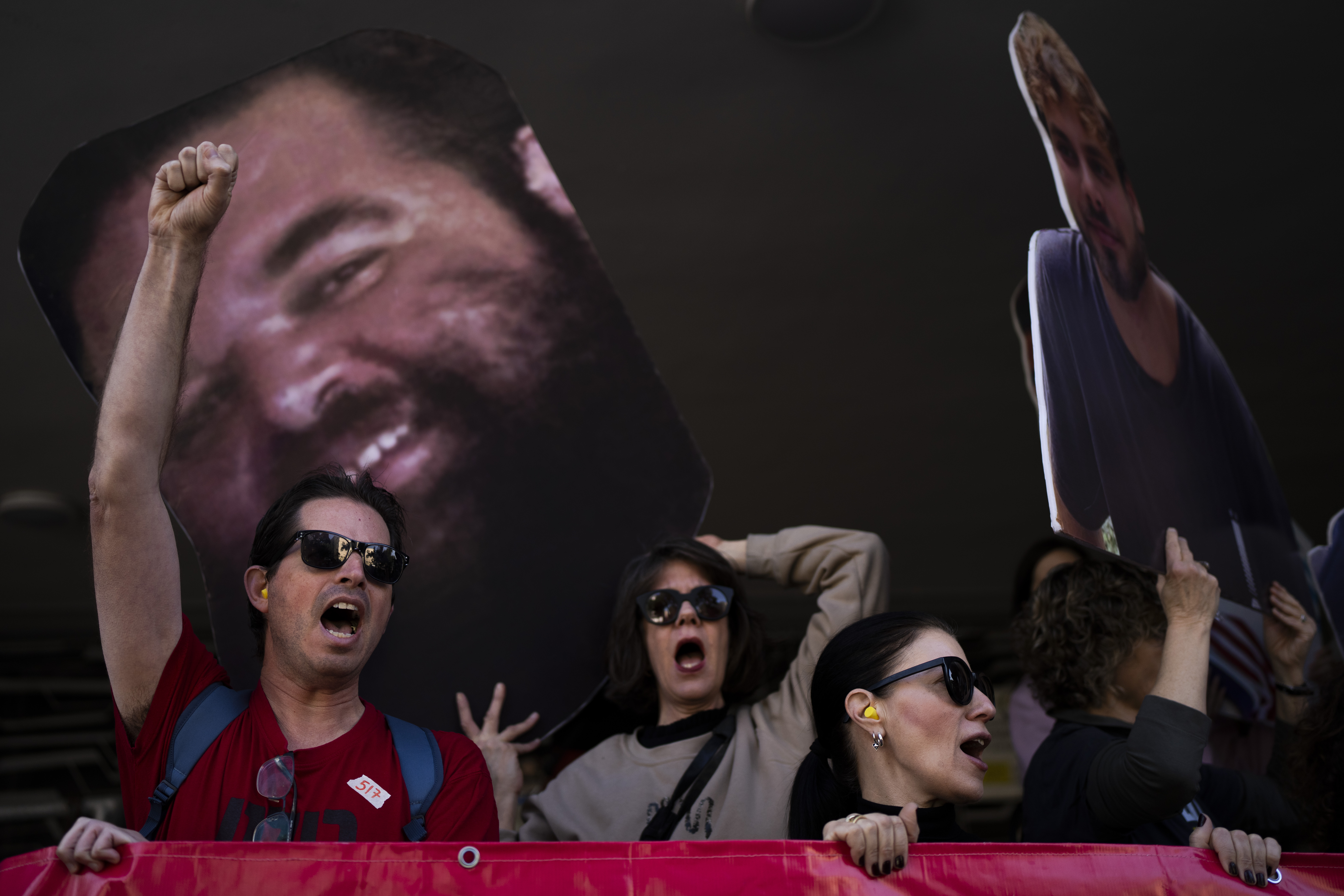 Demonstrators hold photos depicting the faces of Israeli hostages who are being held in the Gaza Strip, during a protest demanding their release from Hamas captivity, in Tel Aviv, Israel, Thursday, March 6, 2025. (AP Photo/Oded Balilty)