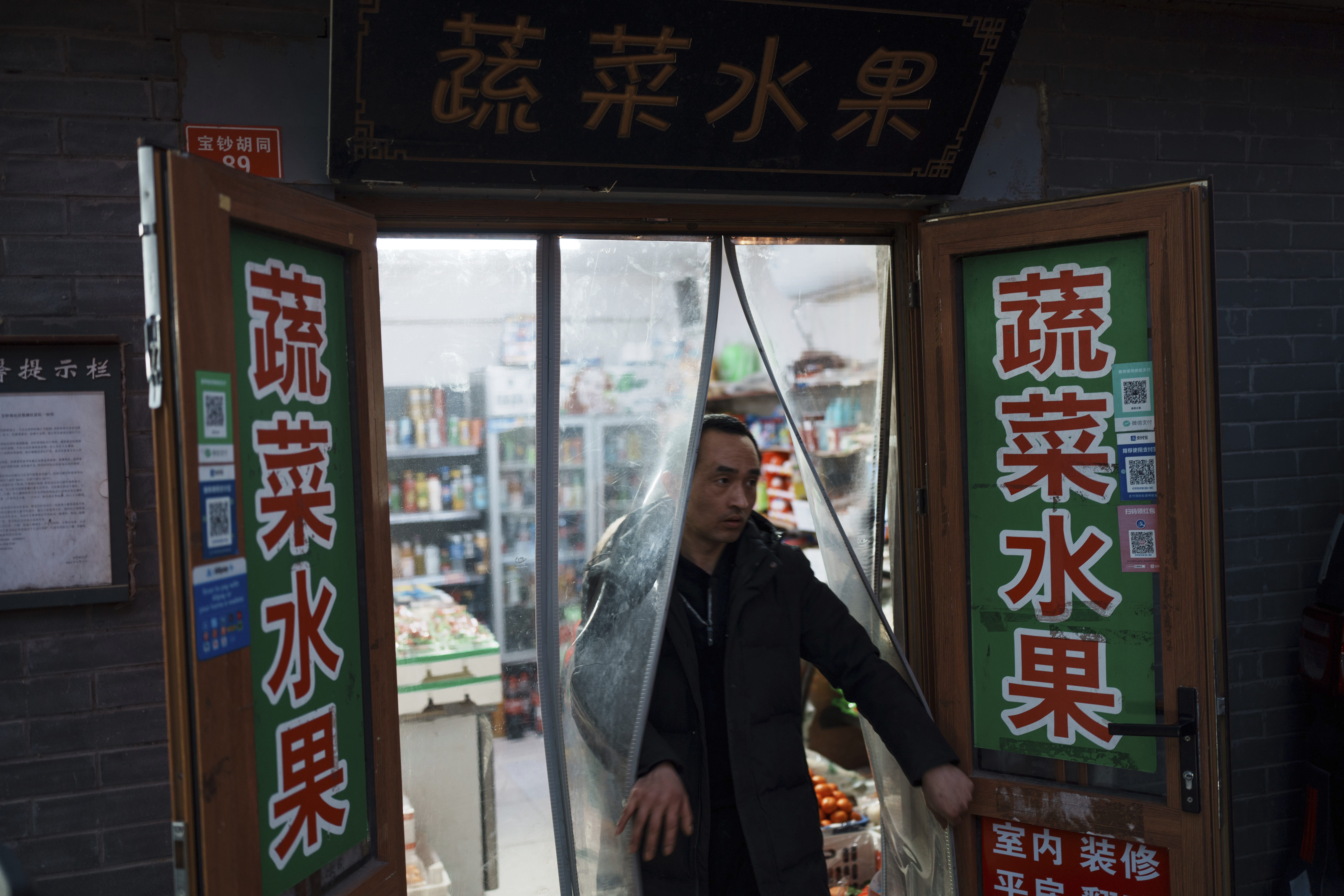 A resident walks out from a local convenience store in downtown Beijing, China, Saturday, March 8, 2025. (AP Photo/Vincent Thian)