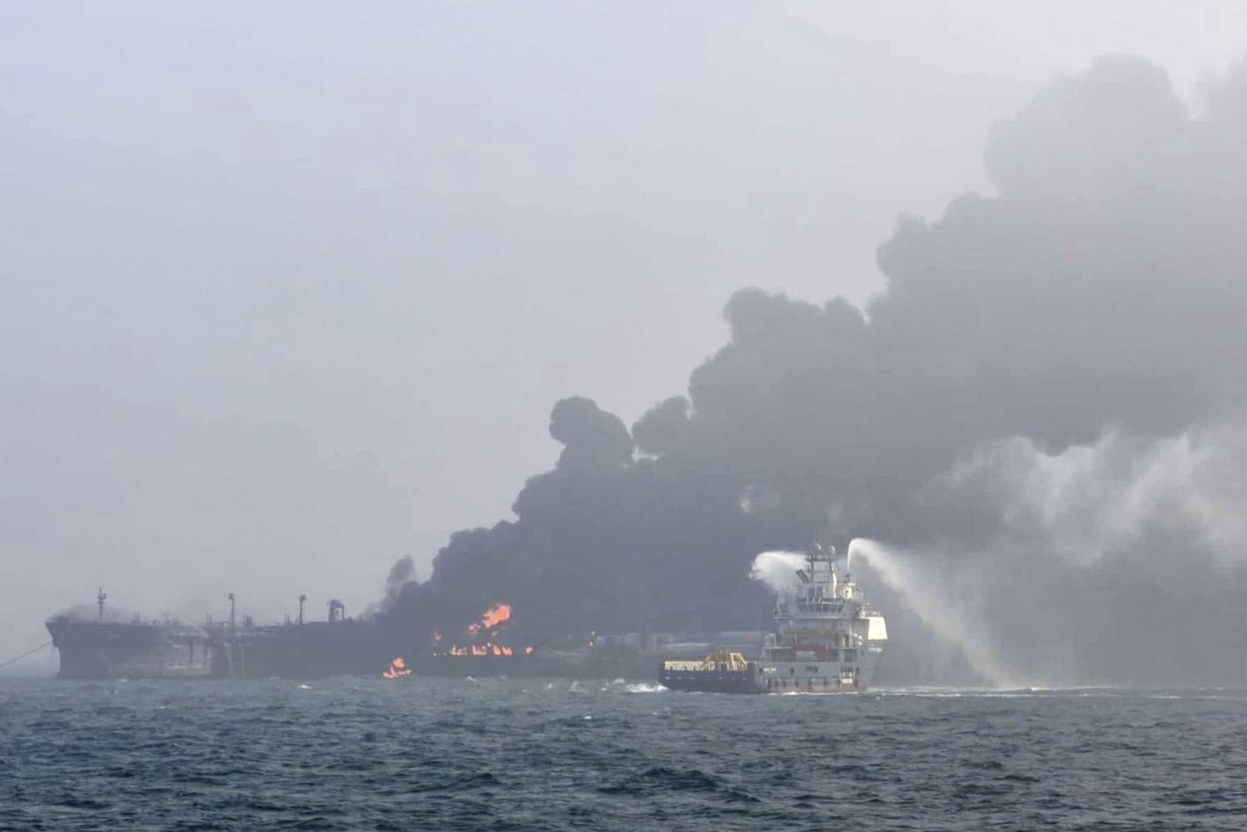 This image provided by Bartek Śmiałek shows a ship trying to extinguish the fire as smoke billows from a vessel after a cargo ship hit a tanker carrying jet fuel off eastern England on Monday, March 10, 2025 setting both ablaze and sending fuel pouring into the North Sea. (Bartek Śmiałek via AP)